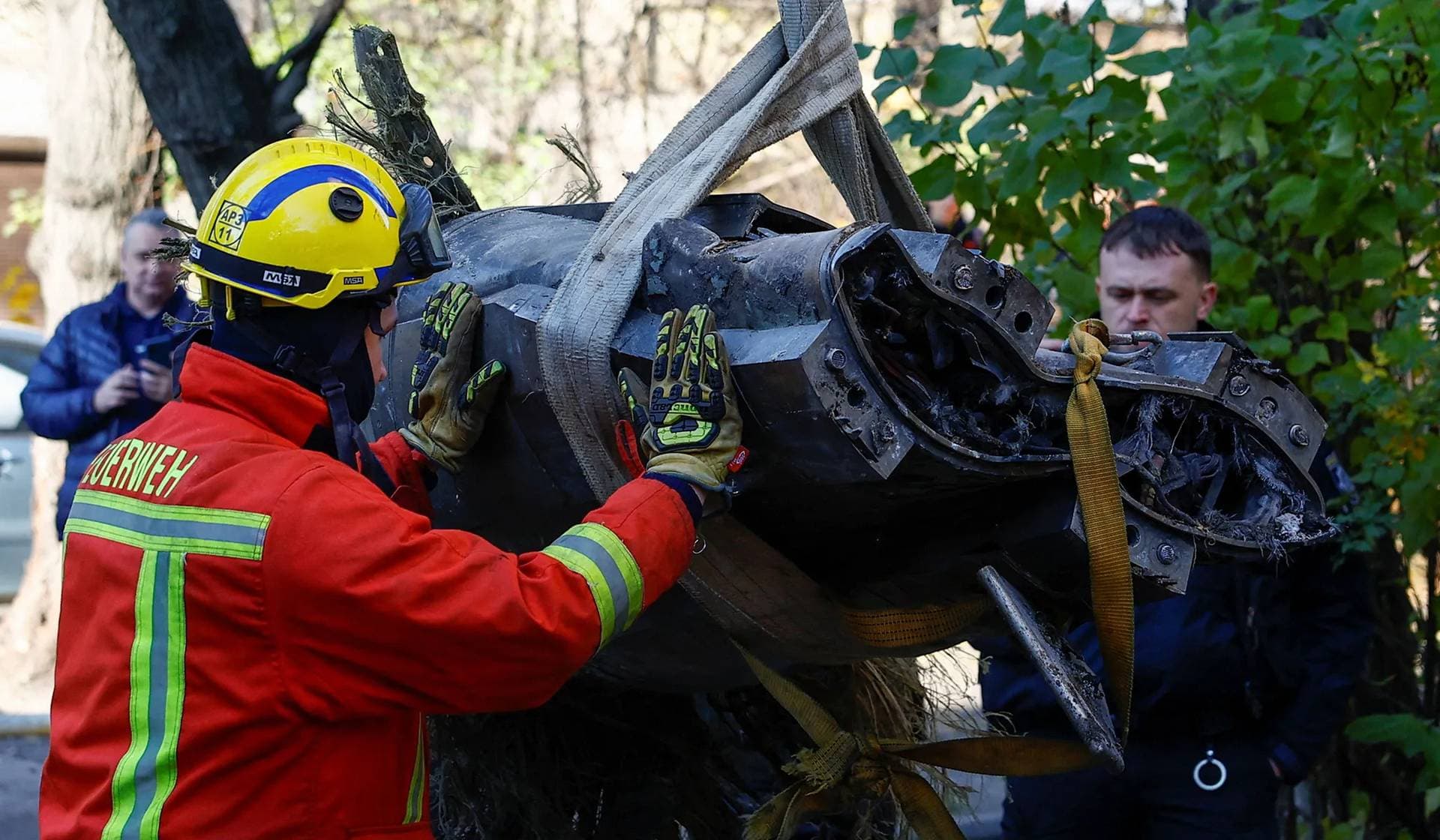 Rescuers carry a part of a Russian missile lifted from an apartment building after a Russian missile strike Kyiv