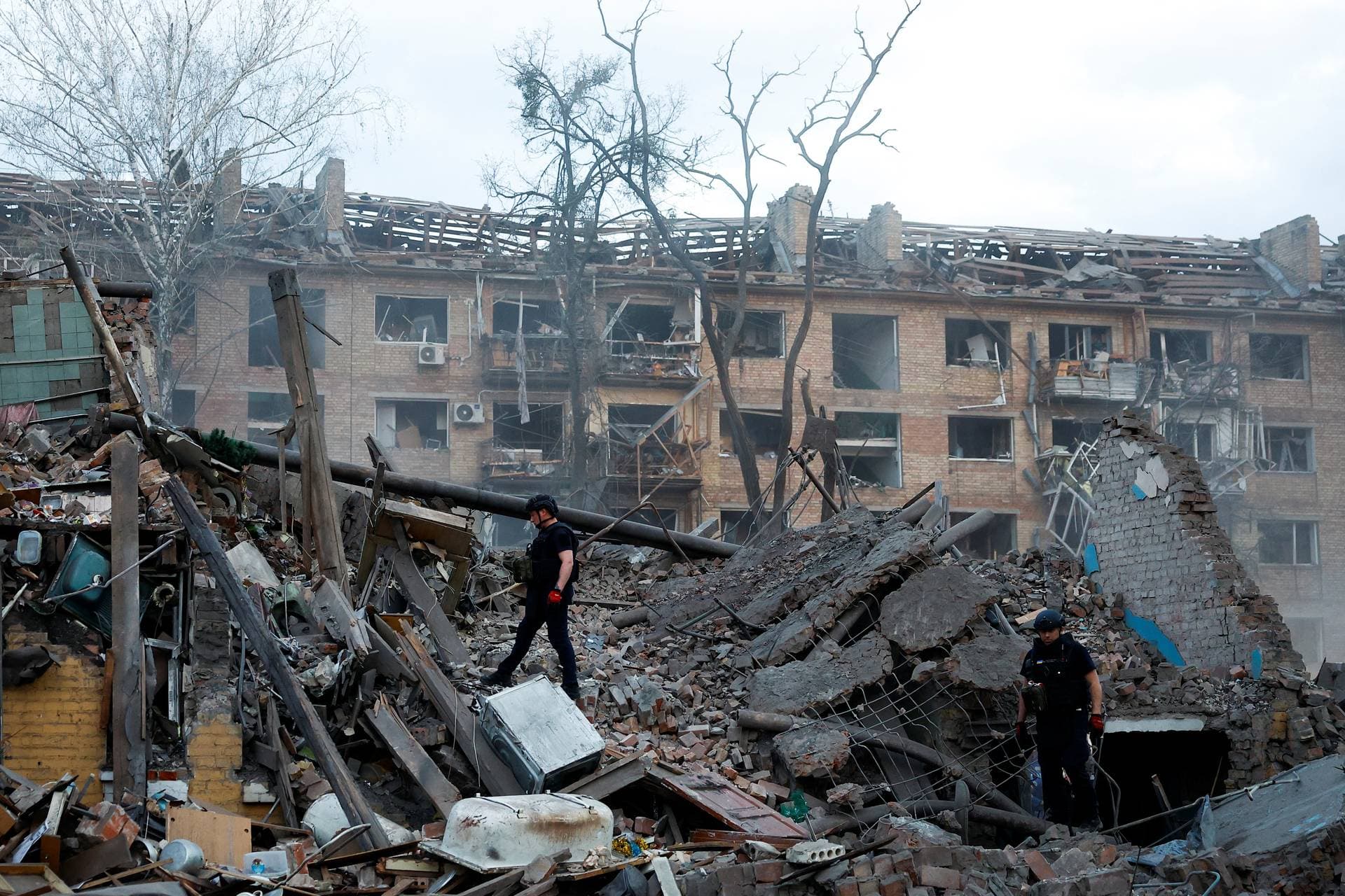 Police officers inspect the site of a building hit by a Russian ballistic missile strike in Kyiv