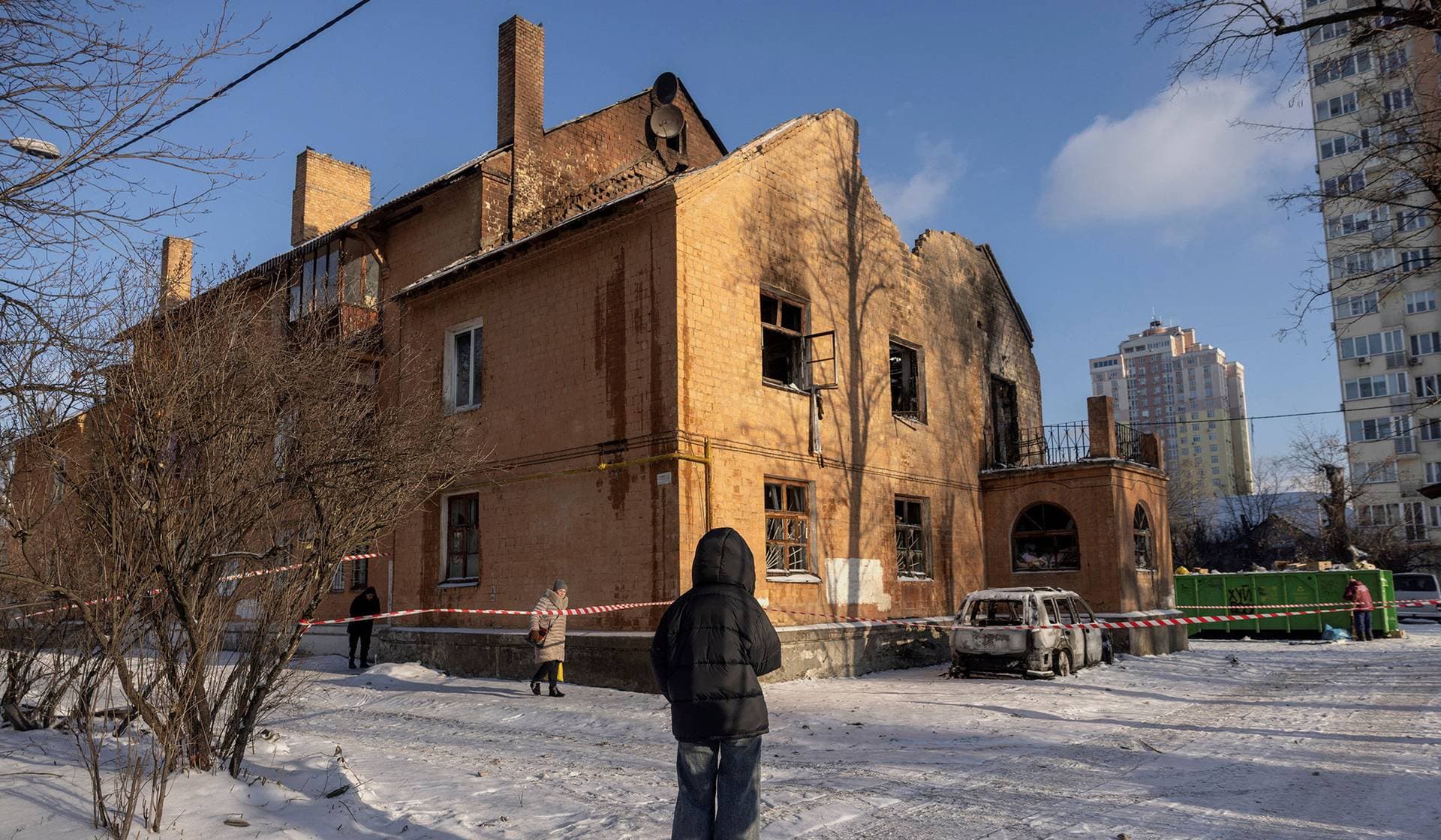A woman looks at a residential building that was partially destroyed after it was hit by a Russian drone in Kyiv