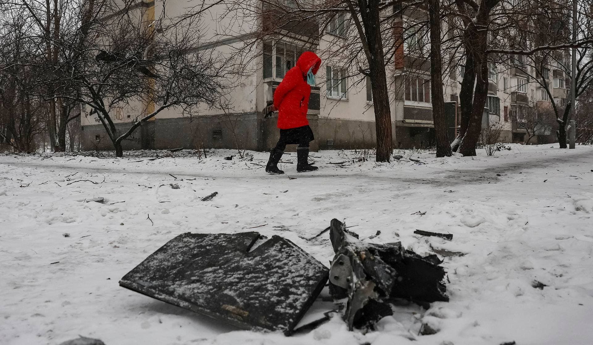 A resident walks near a part of a Russian drone at the site of the apartment building hit by a Russian drone strike in Kyiv