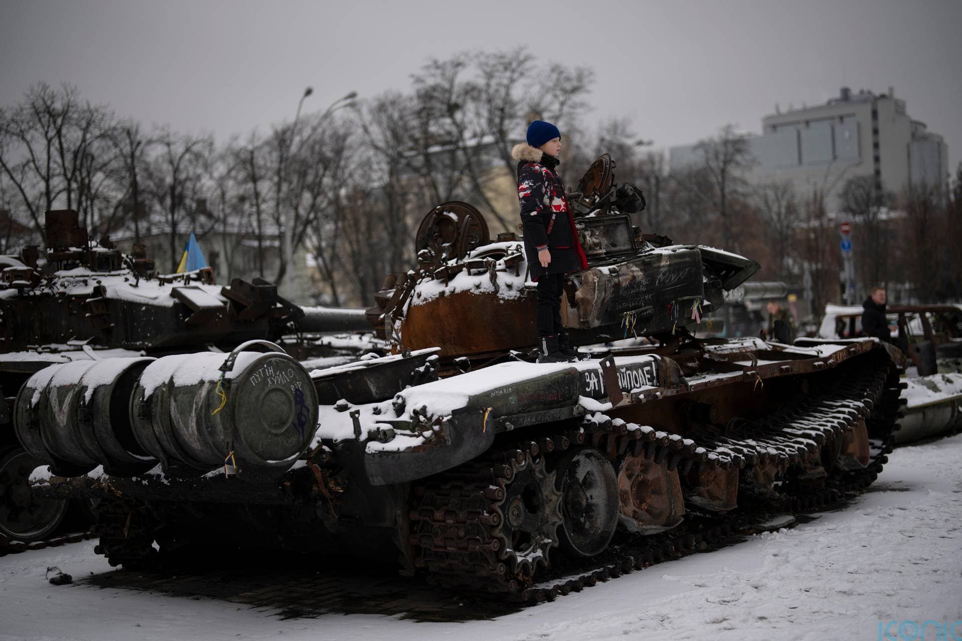 A boy stands on a destroyed Russian tank displayed in downtown Kyiv