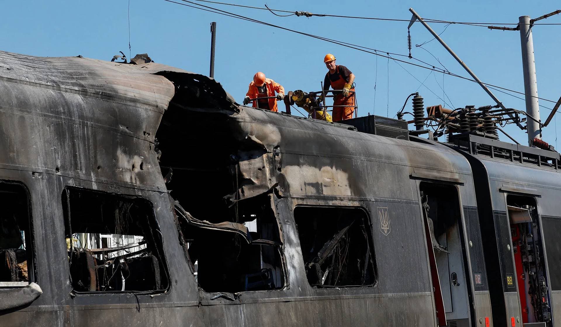 Workers inspect a Ukrainian Railways HRCS2 Hyundai Rotem train hit by a Russian drone strike in Kyiv