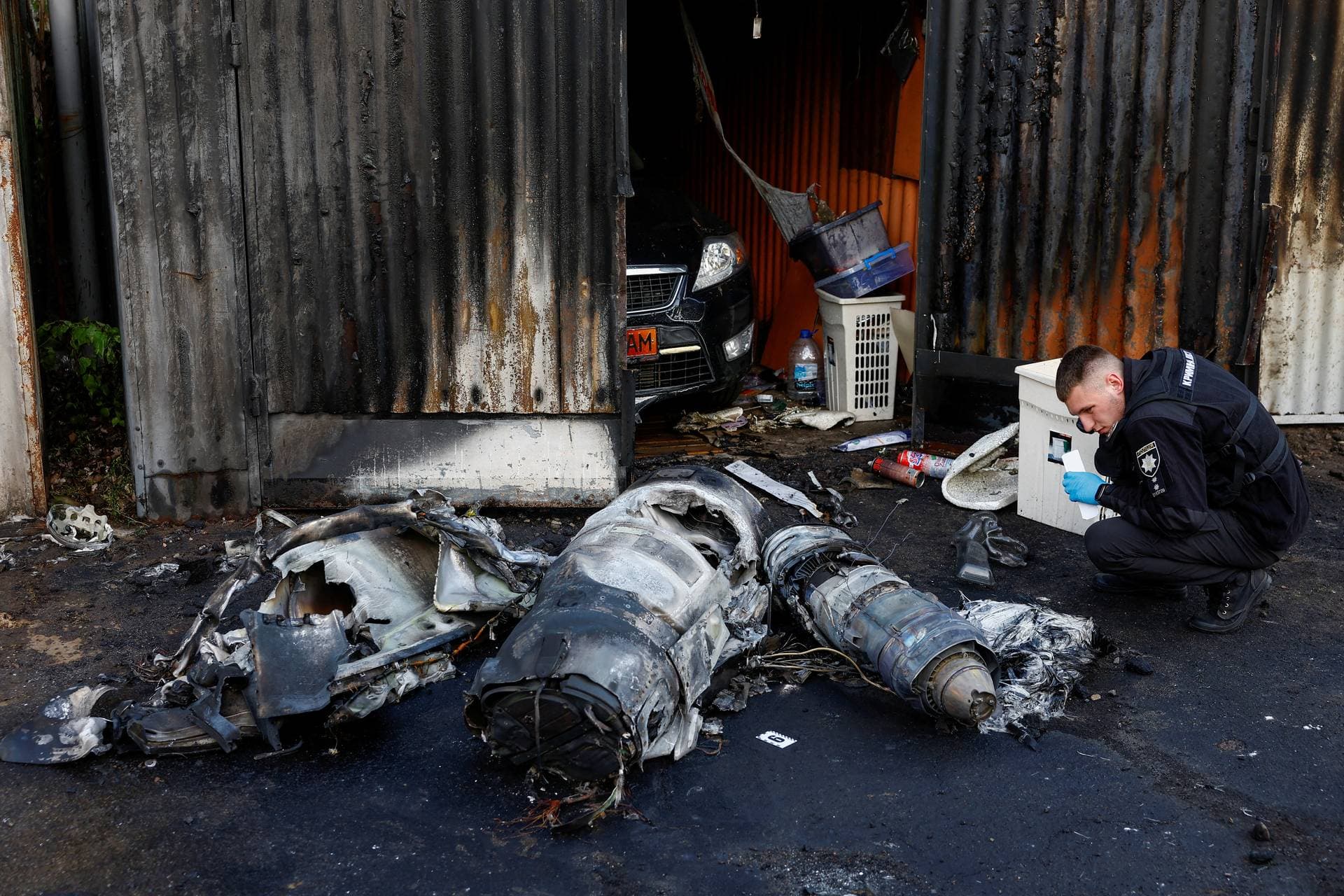 A police officer inspects the remains of a Russian cruise missile shot down by Air Defence Forces in Kyiv