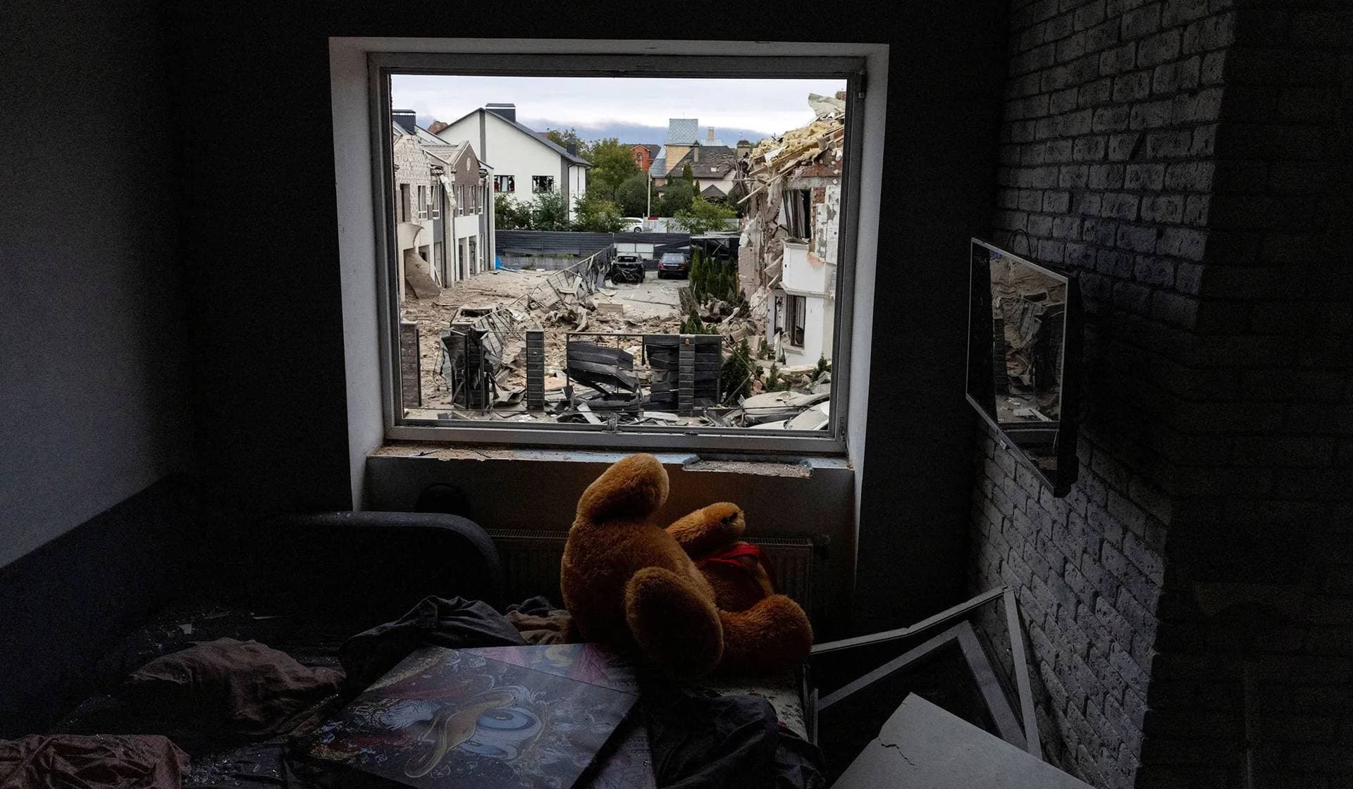 A teddy bear lies on a bed covered in shards of glass and debris after a projectile struck residential buildings across the street during Russian drone and missile strikes in Kyiv
