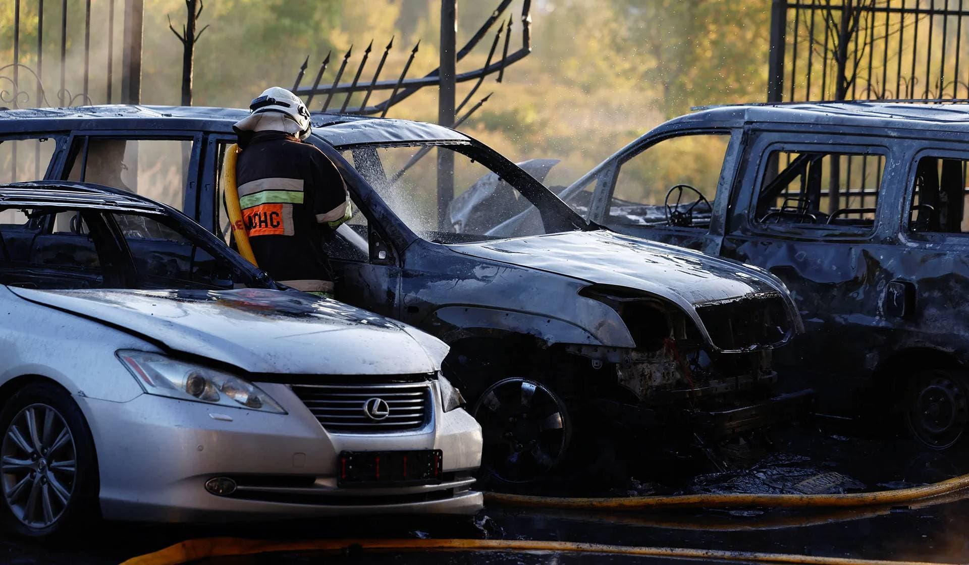 A firefighter works near damaged vehicles at the site of a residential building damaged during a Russian drone and missile strike in outskirts of Kyiv