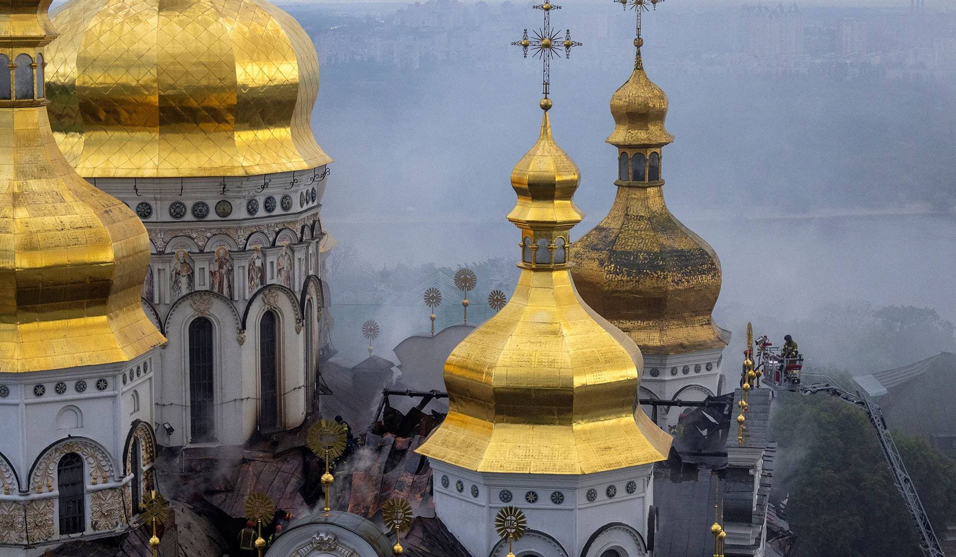 Emergency workers extinguish a fire on the roof of the Dormition Cathedral of the Kyiv Pechersk Lavra after it was hit during Russian missile and drone strikes in Kyiv