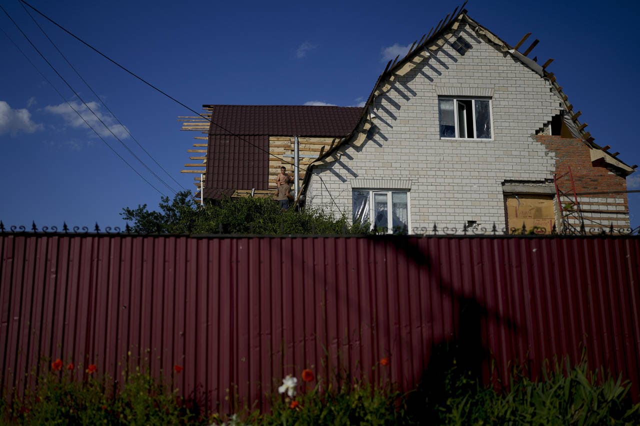 Men fix a roof at a house destroyed by attacks in Gorenka
