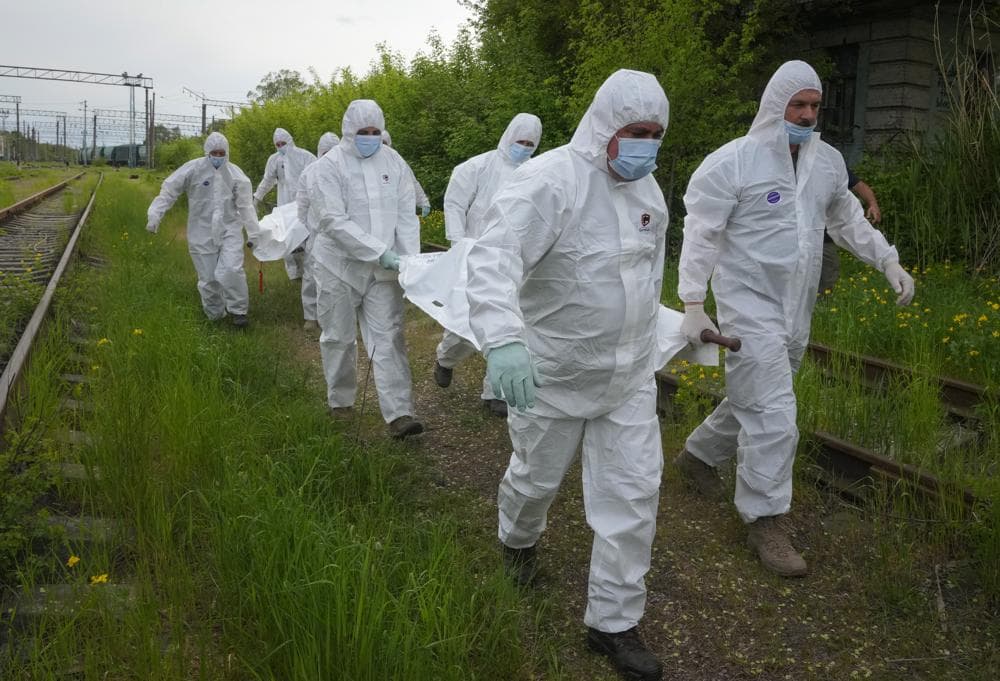 Ukrainian servicemen carry bodies of Russian soldiers to load into a railway refrigerator carriage in Kyiv