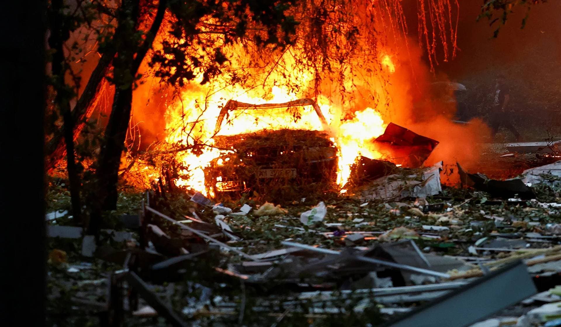 A car damaged during Russian missile and drone strikes burn in Kyiv