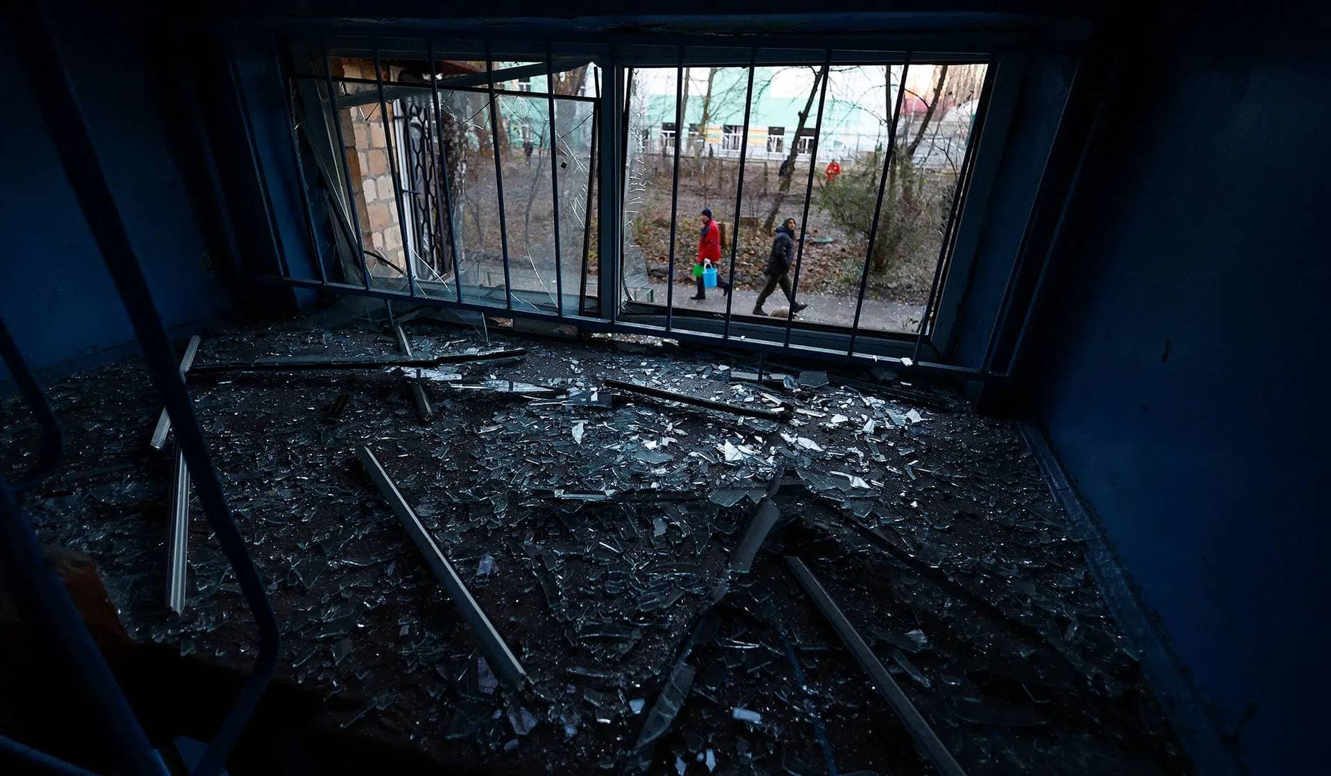 Local residents walk in front of their apartment building damaged during Russian drone strikes in Kyiv