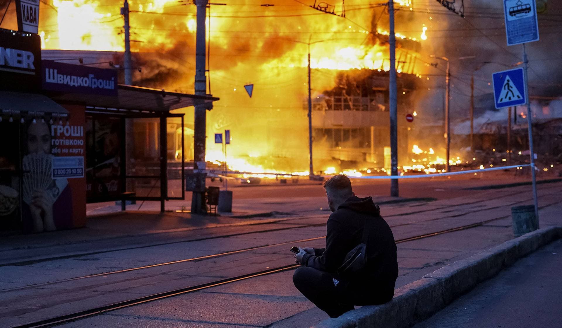 A resident sits at a site of a Russian missile and drone strike in Kyiv