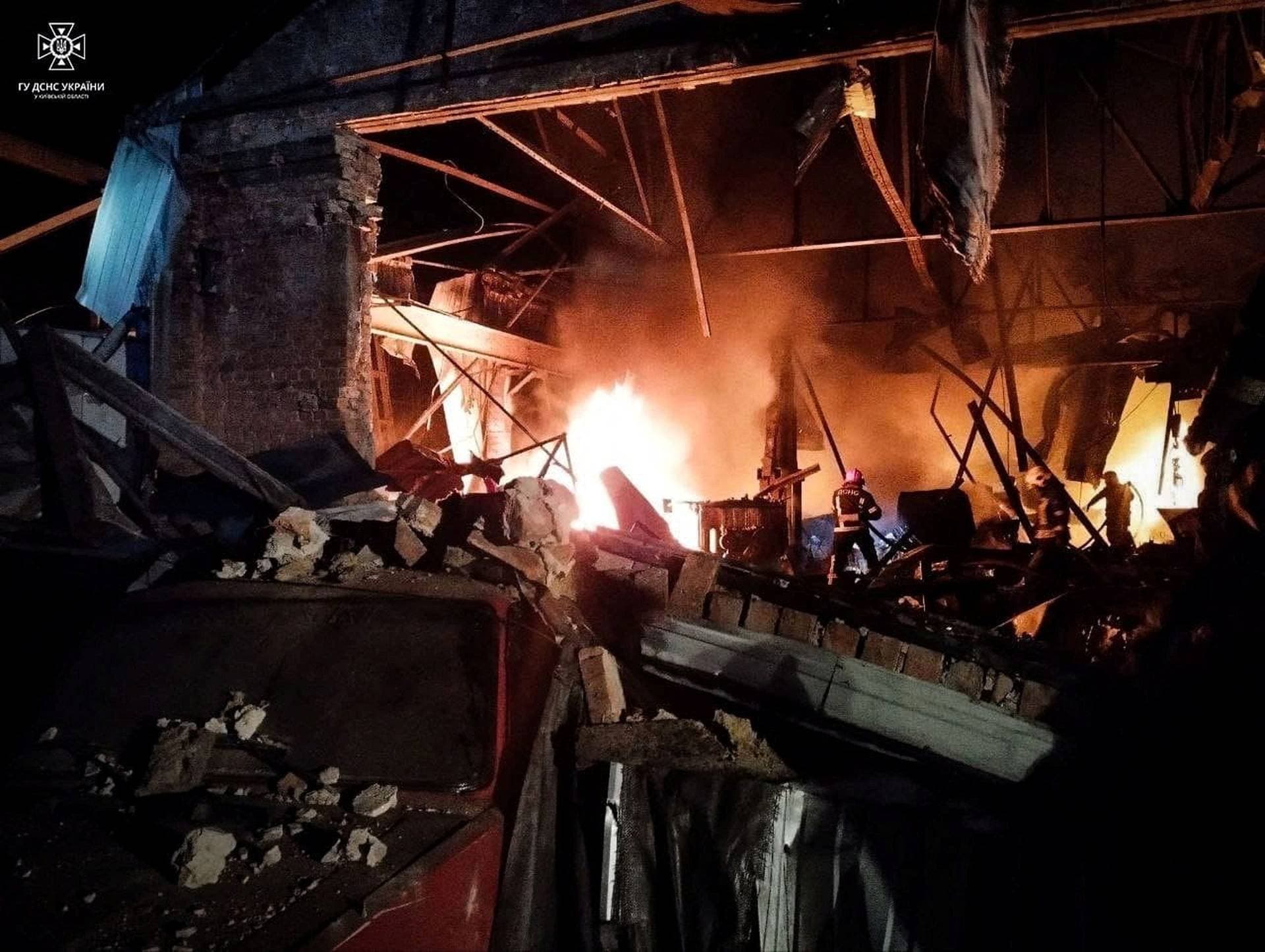 Firefighters work at a site of a warehouse heavily damaged during a Russian drone strike in Kyiv region