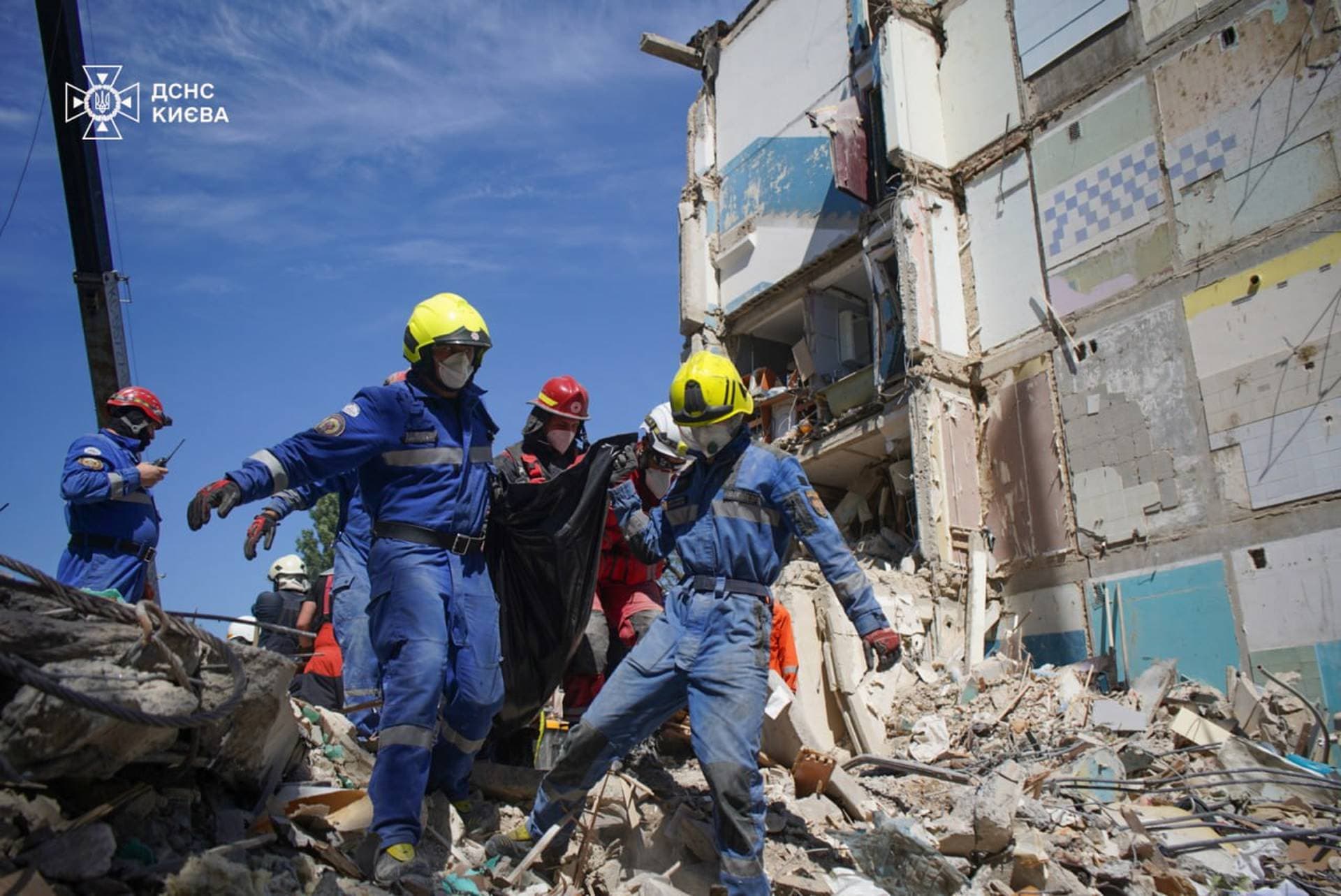 Rescuers carry the body of a person found under debris at the site where an apartment building was hit by a Russian missile strike in Kyiv