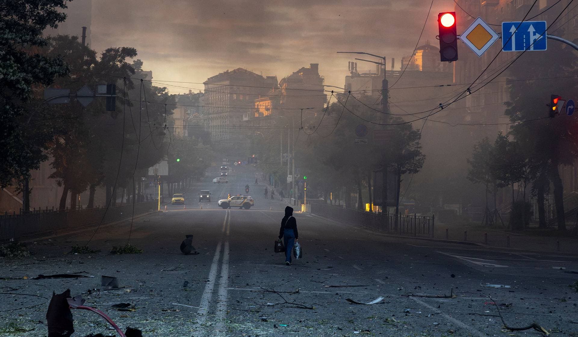 A woman walks on a debris-scattered street in the aftermath of an overnight Russian missile and drone strike in Kyiv