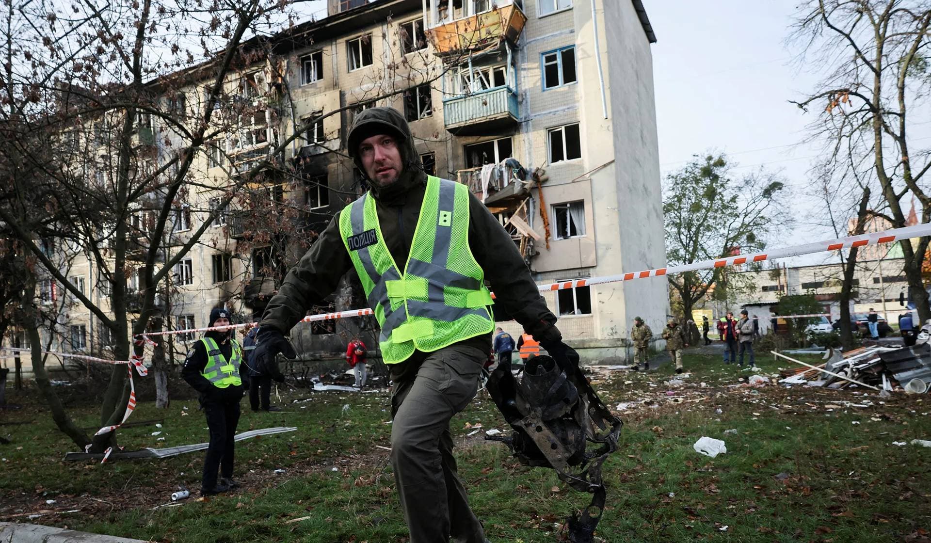 An investigator carries a part of a Russian Shahed drone at the site of an apartment building damaged during an overnight Russian drone and missile strike in Kyiv