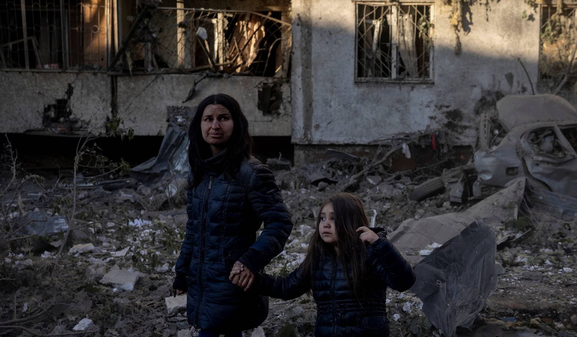 Olha Mudra and her six-year-old daughter Nataliia walk past their damaged apartment building in Kyiv