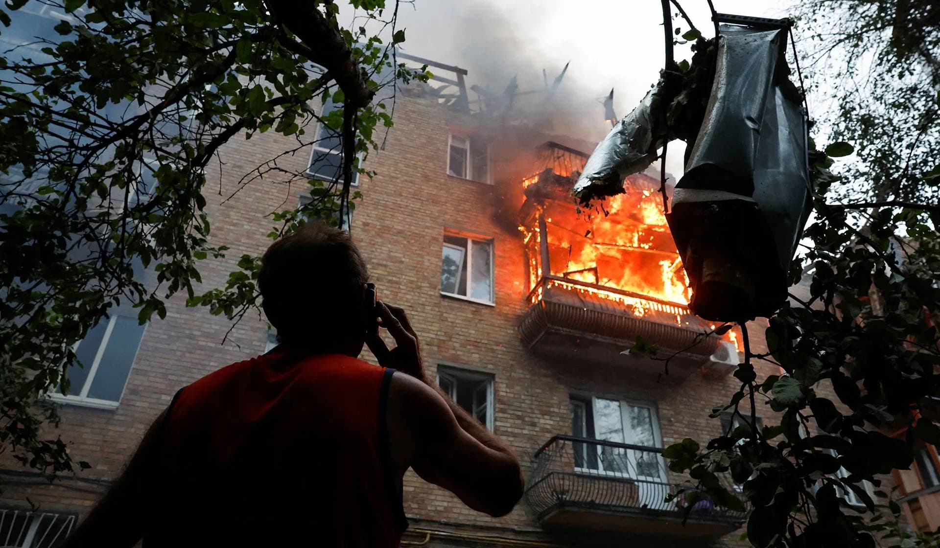 A resident looks on at the site of an apartment building hit during Russian missile and drone strikes in Kyiv