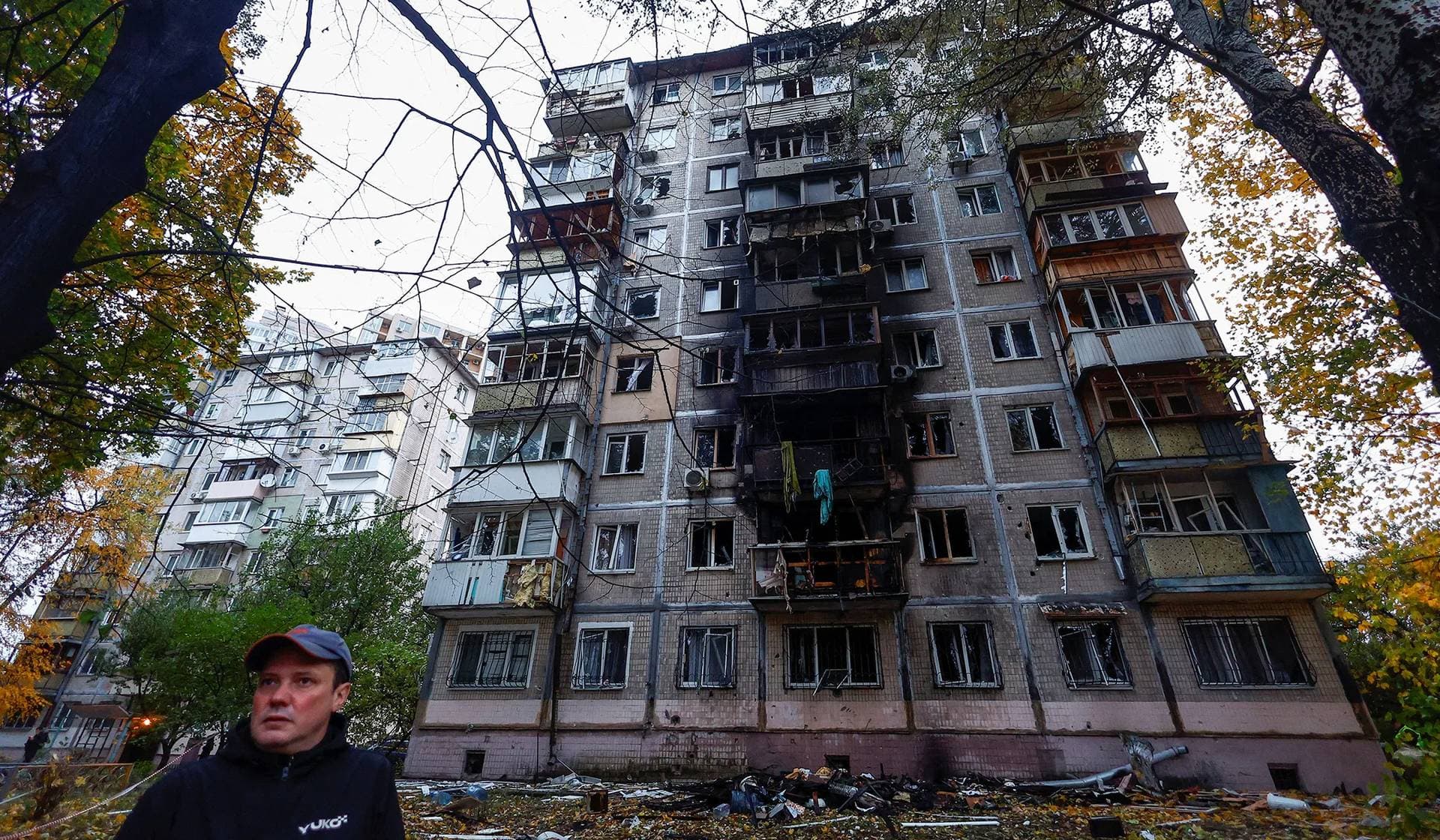 A resident stands in front of an apartment building damaged by a Russian drone strike in Kyiv