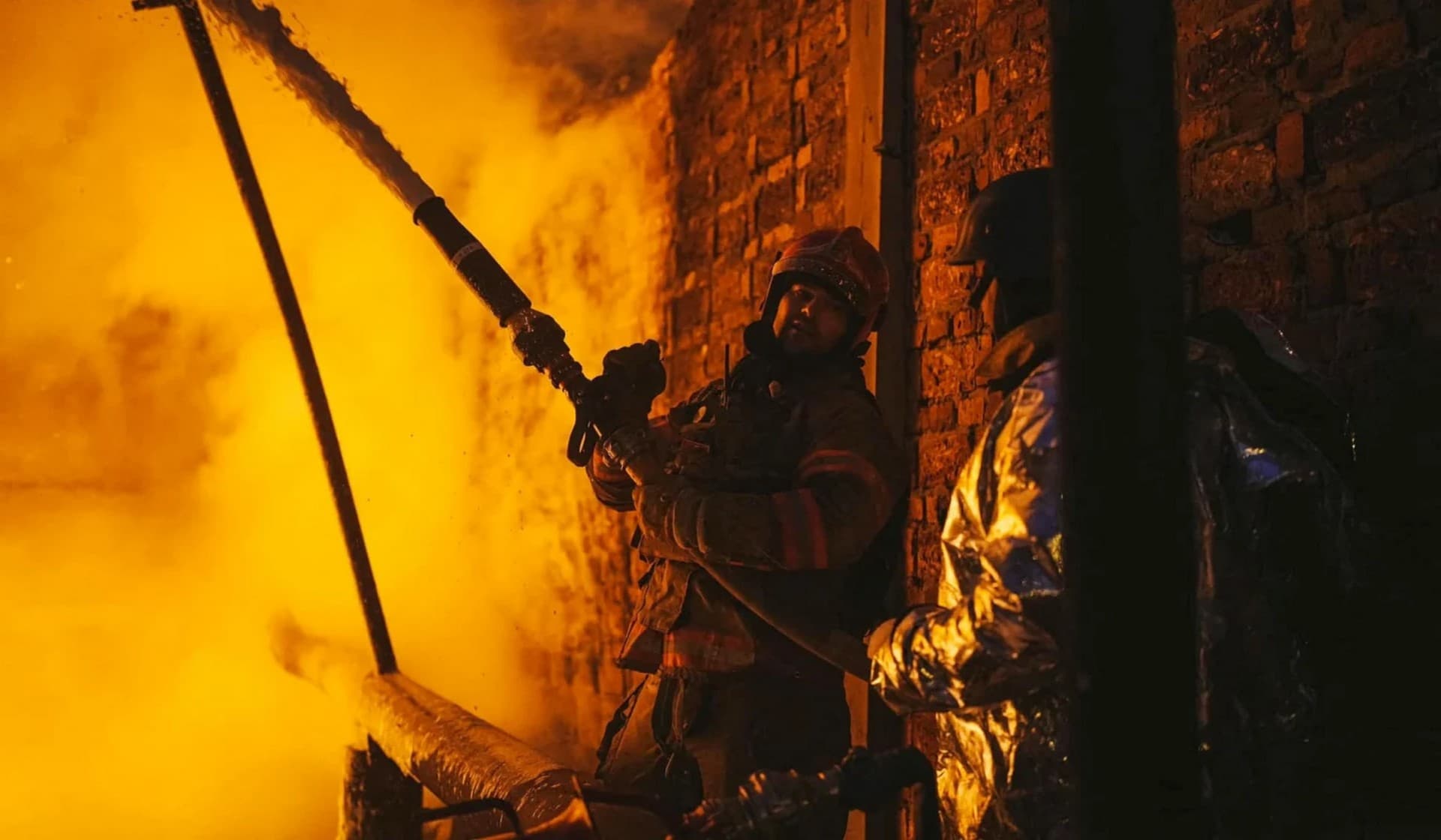 Firefighters work at a site of critical power infrastructure hit during Russia's drones attacks in Kyiv