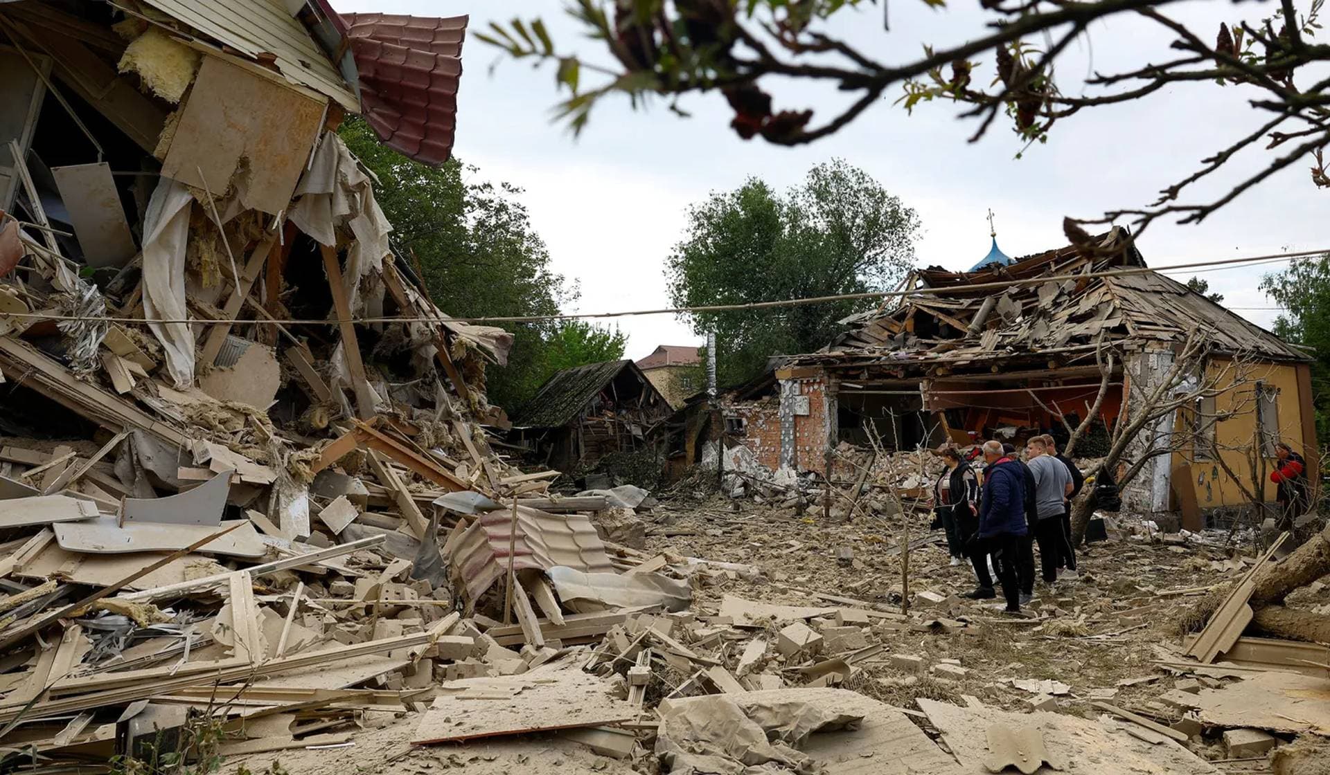 Residents stand next to houses heavily damaged by a Russian drone strike outside of Kyiv