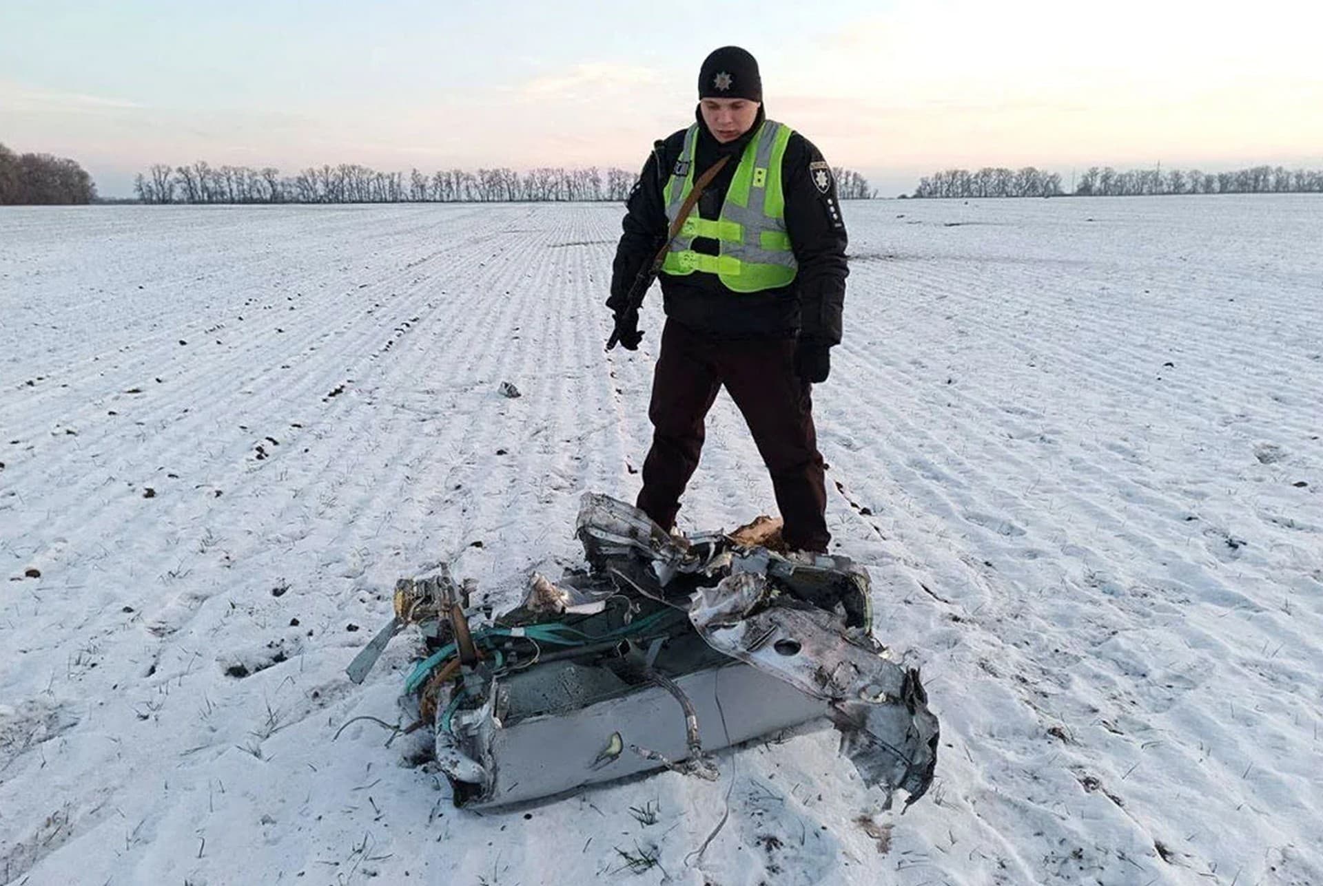A police officer stands next to a part of a Russian cruise missile shot down by the Ukrainian Air Defence Forces in Kyiv Region