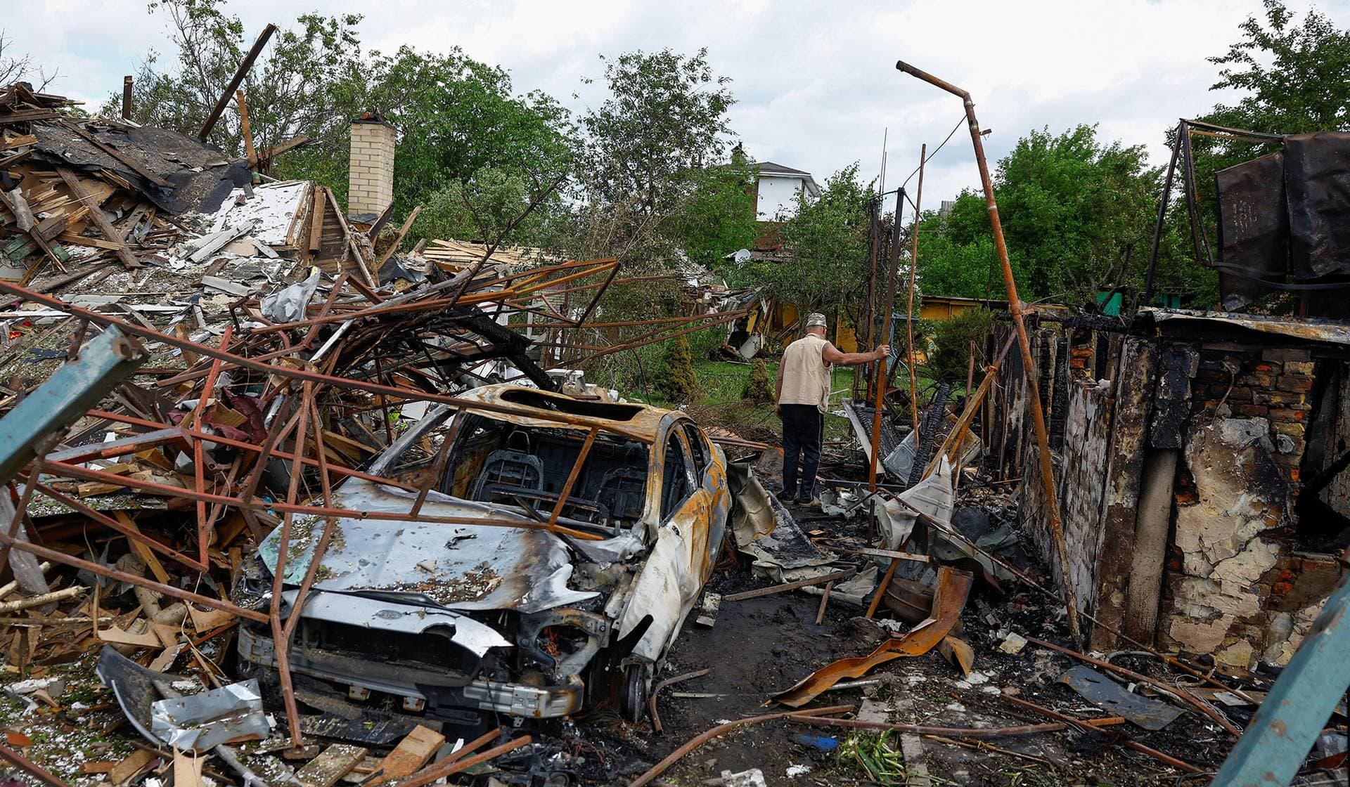 Resident Vasyl inspects a yard of his neighbours, which was damaged during Russian missile and drone strikes in Kyiv