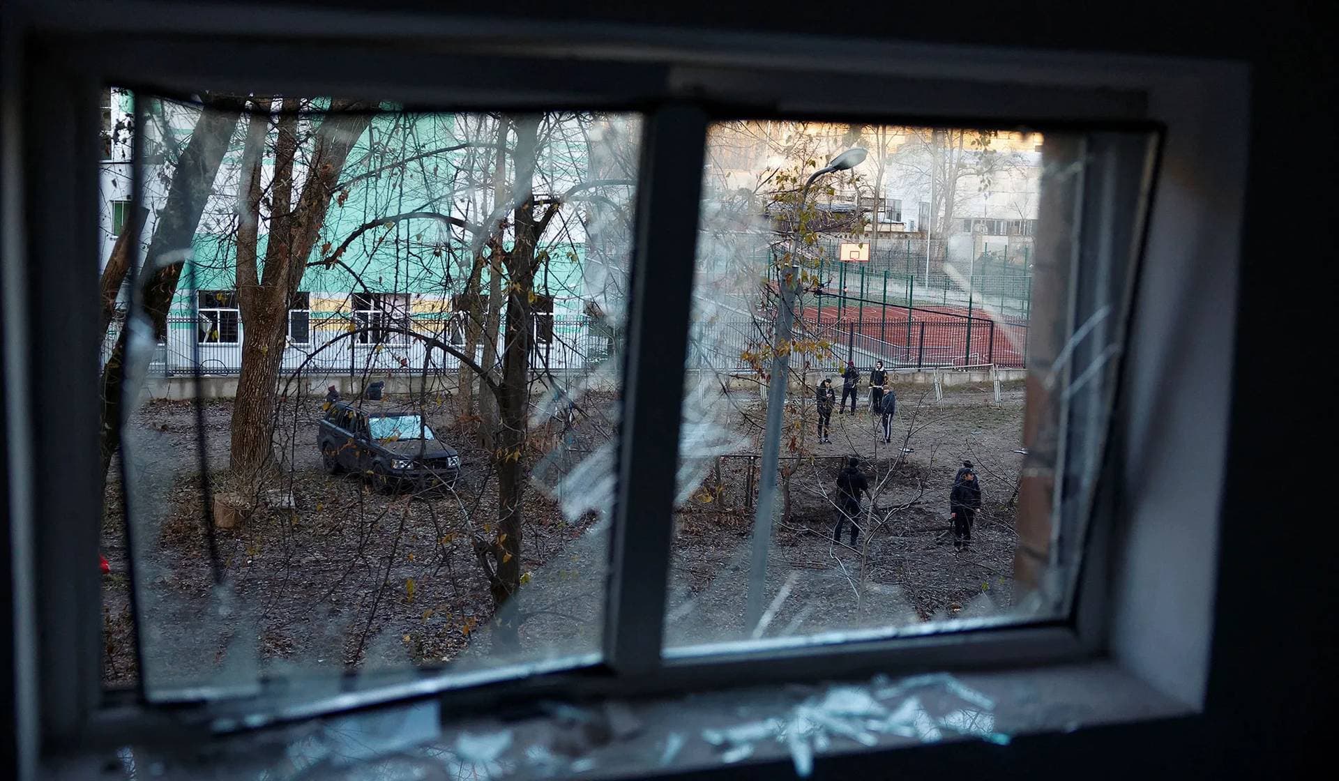 Local residents stand next to a crater that appeared following Russian drone strikes in Kyiv