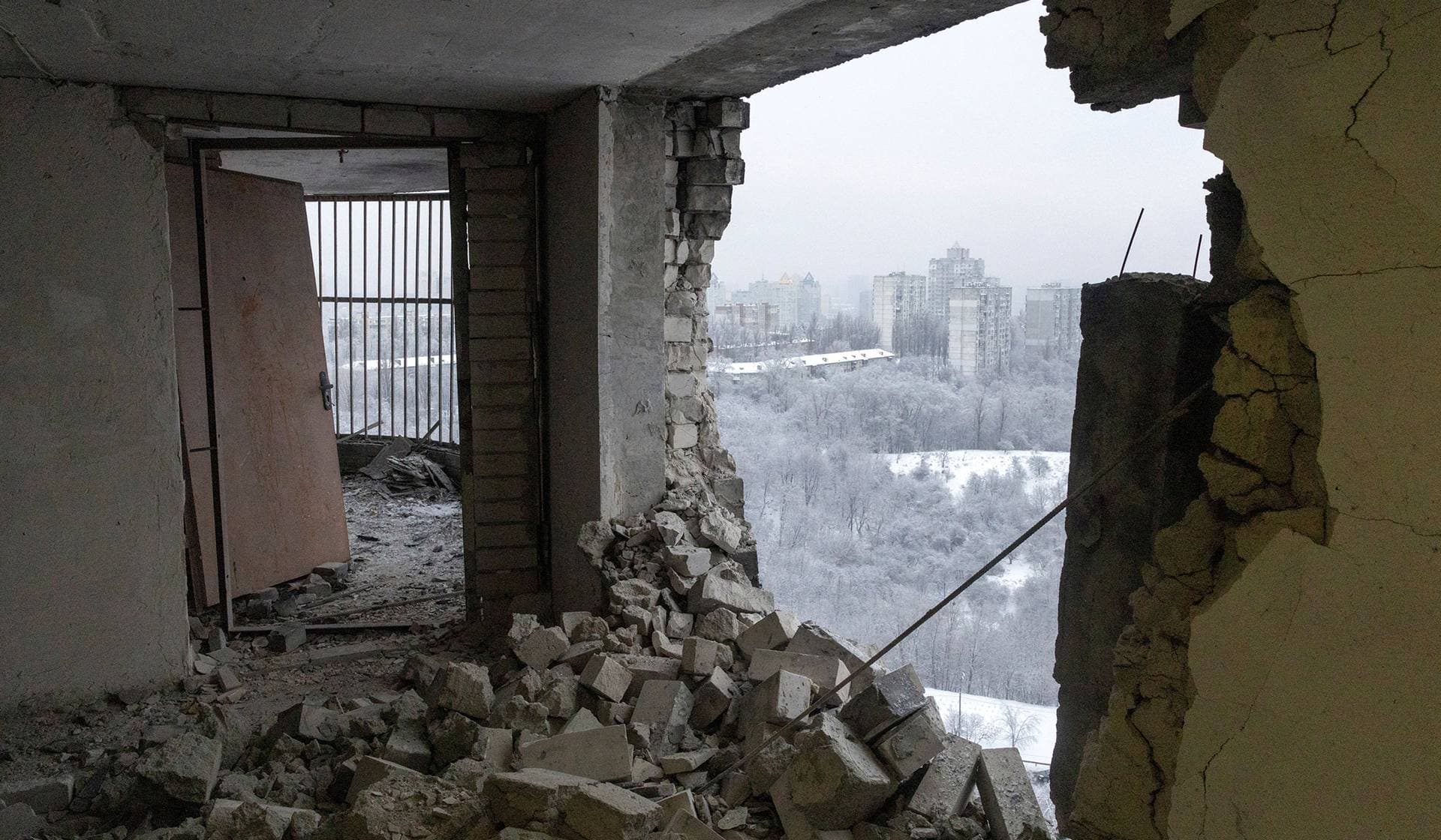 The snow-covered capital seen through the impact hole of a Russian drone that hit the top floor of an apartment building in Kyiv