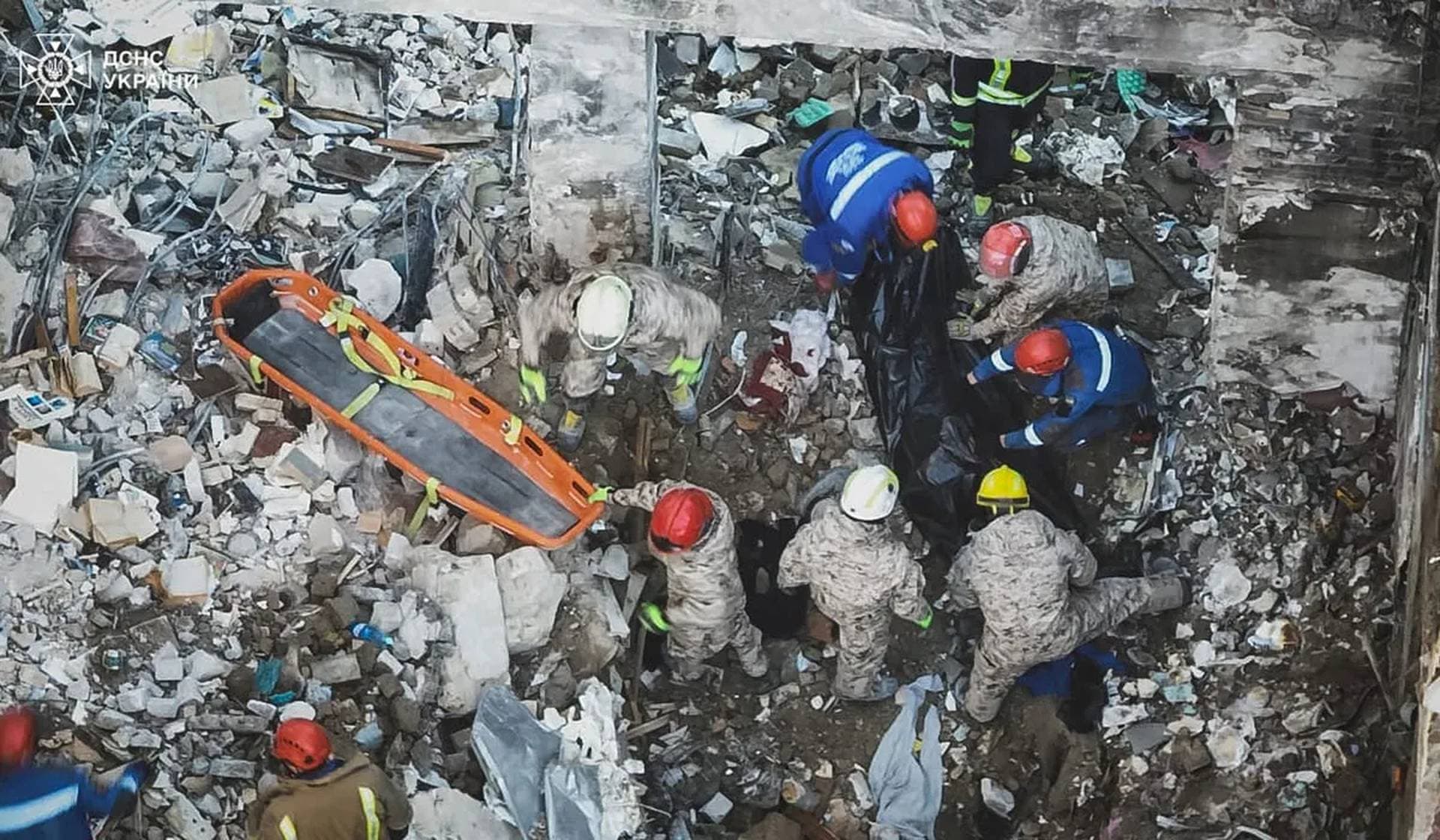 Rescuers prepare to carry the body of a person found under debris of an apartment building in Kyiv