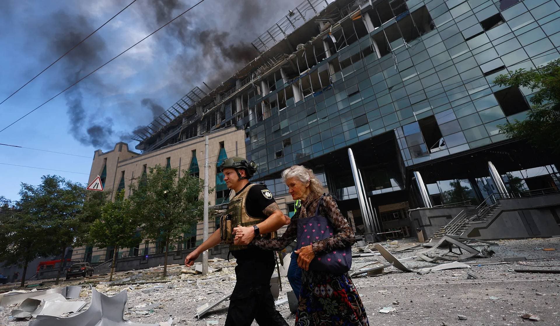 A police officer assists a woman near a building damaged during Russian missile strikes in Kyiv