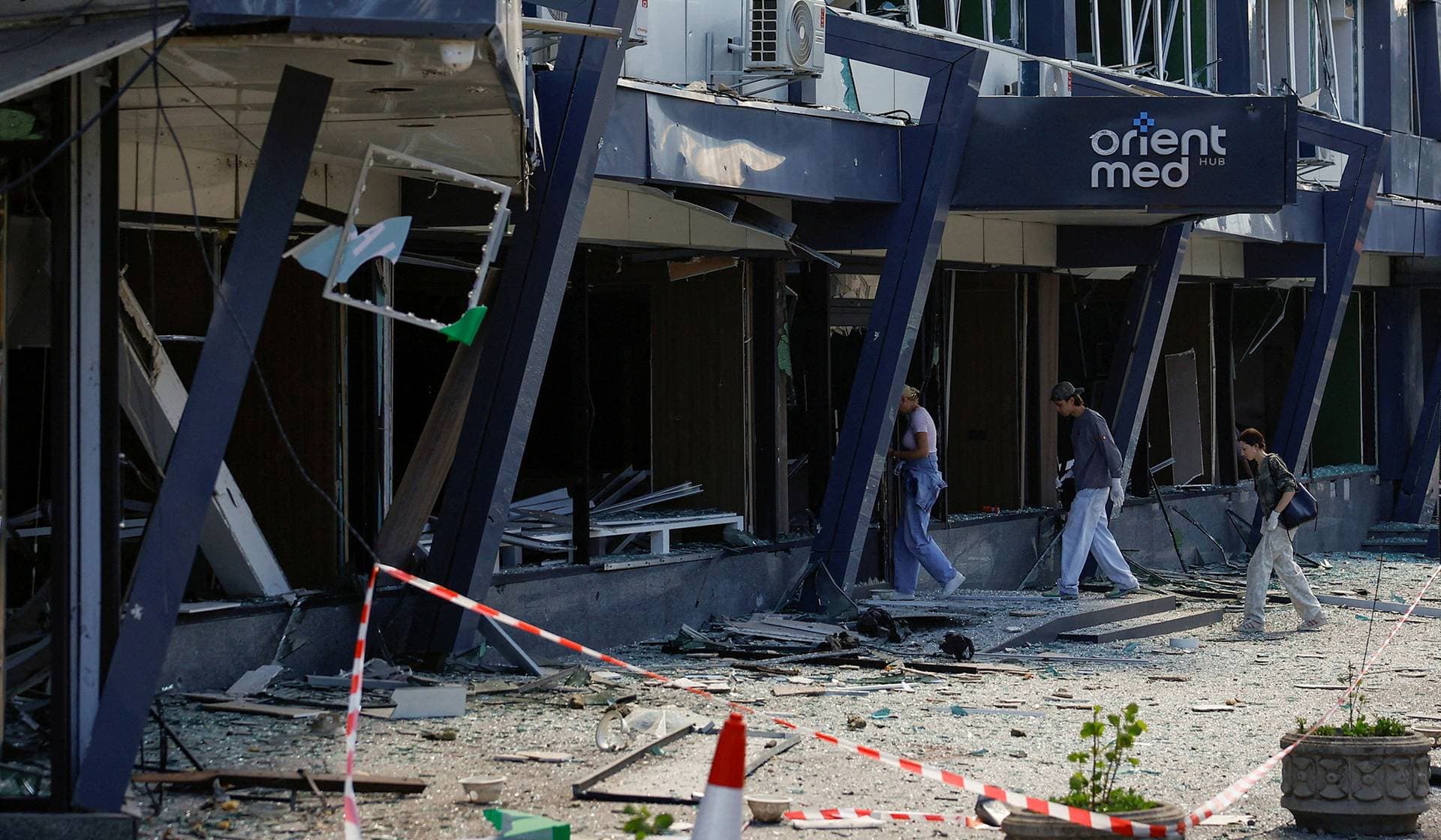Employees walk into a building of a private medical clinic damaged during Russian missile and drone strikes in Kyiv