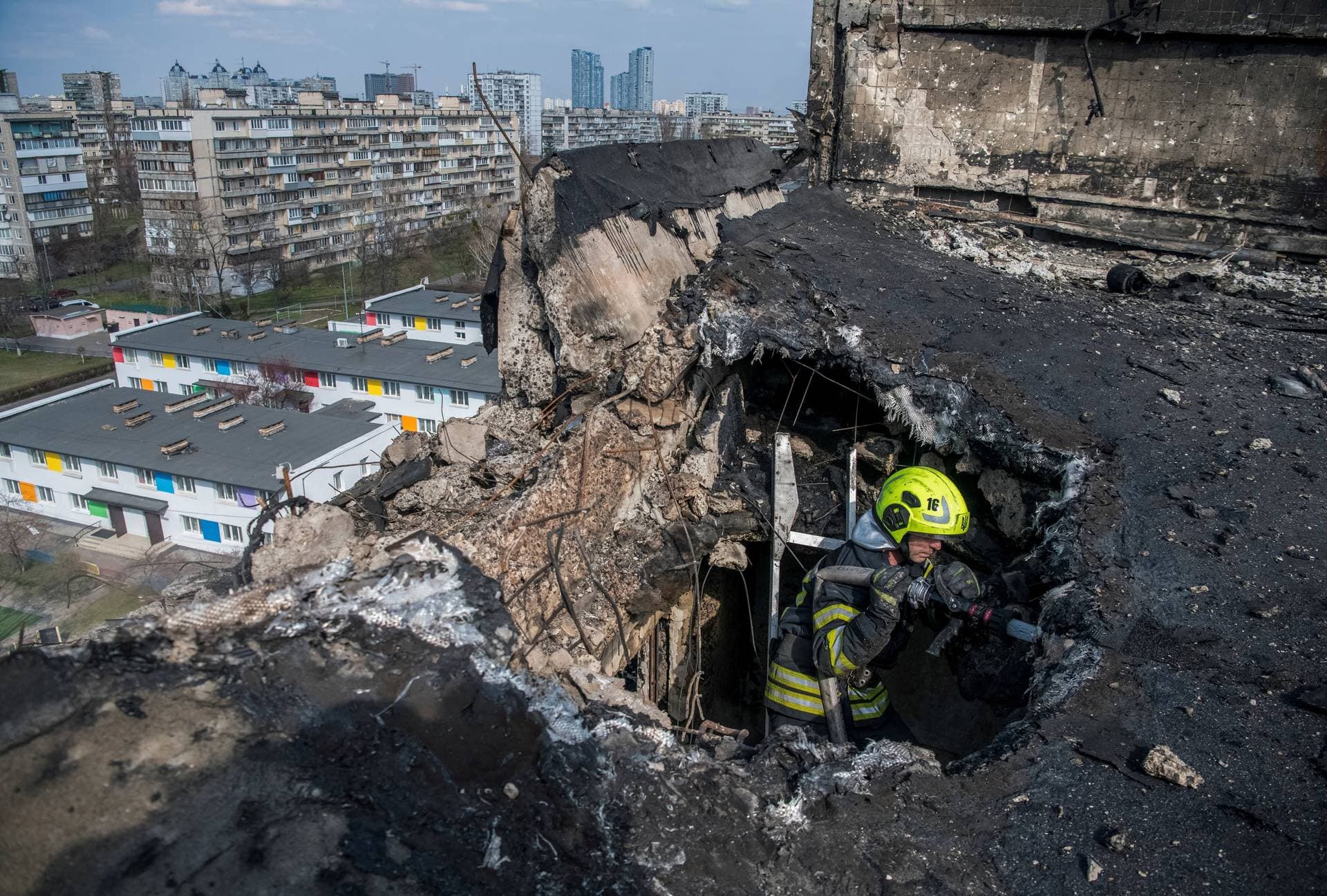 A firefighter works at a site an apartment building hit by a Russian drone strike in Kyiv
