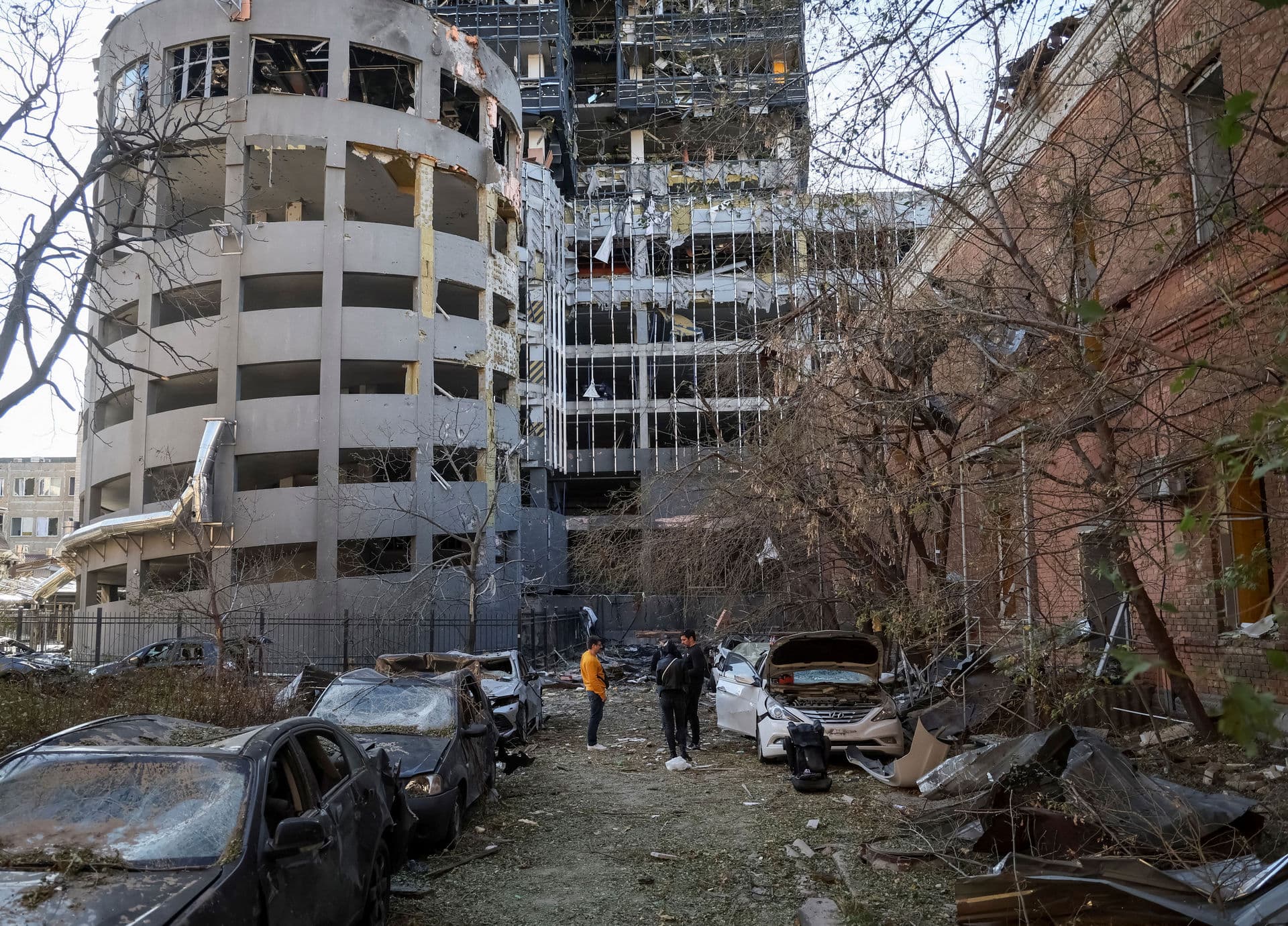Local residents stand next to their destroyed car in central Kyiv