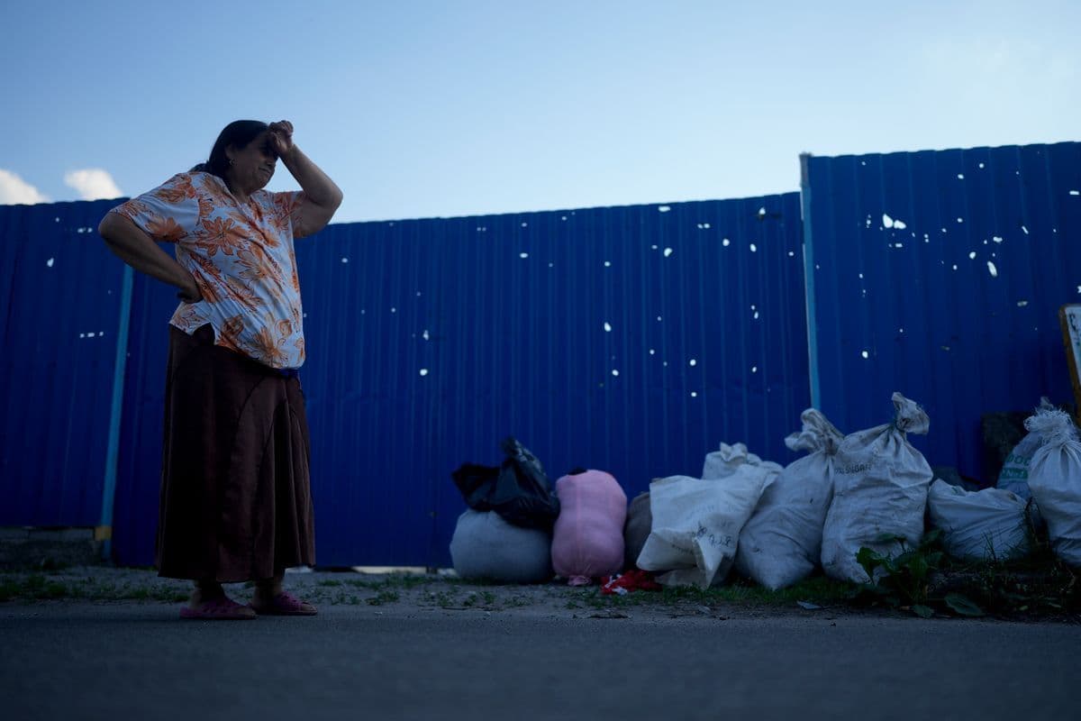 A woman holds her head as she clear her house of rubble after attacks in Gorenka