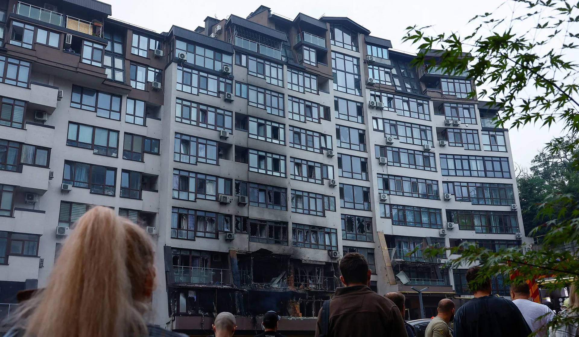 Residents stand next to their apartment building hit by a Russian drone strike in Kyiv