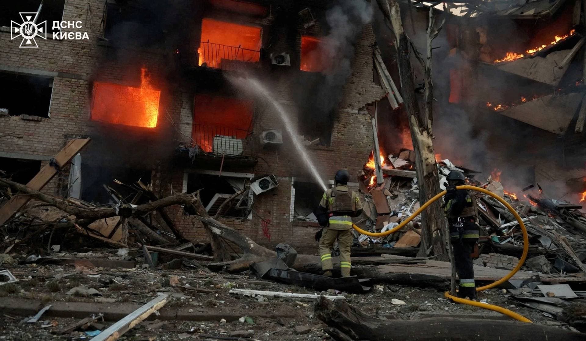 Firefighters work at a site of a building damaged during a Russian missile and drone strike at a location provided as Kyiv