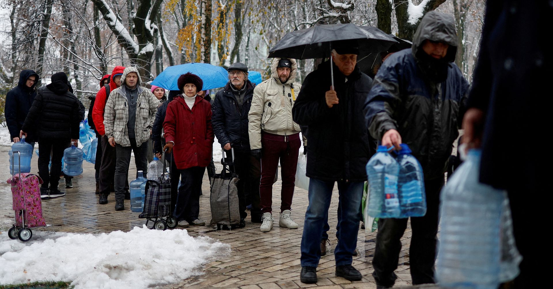 Local residents stand in line to fill up bottles with fresh drinking water after critical civil infrastructure was hit by Russian missile attacks in Kyiv