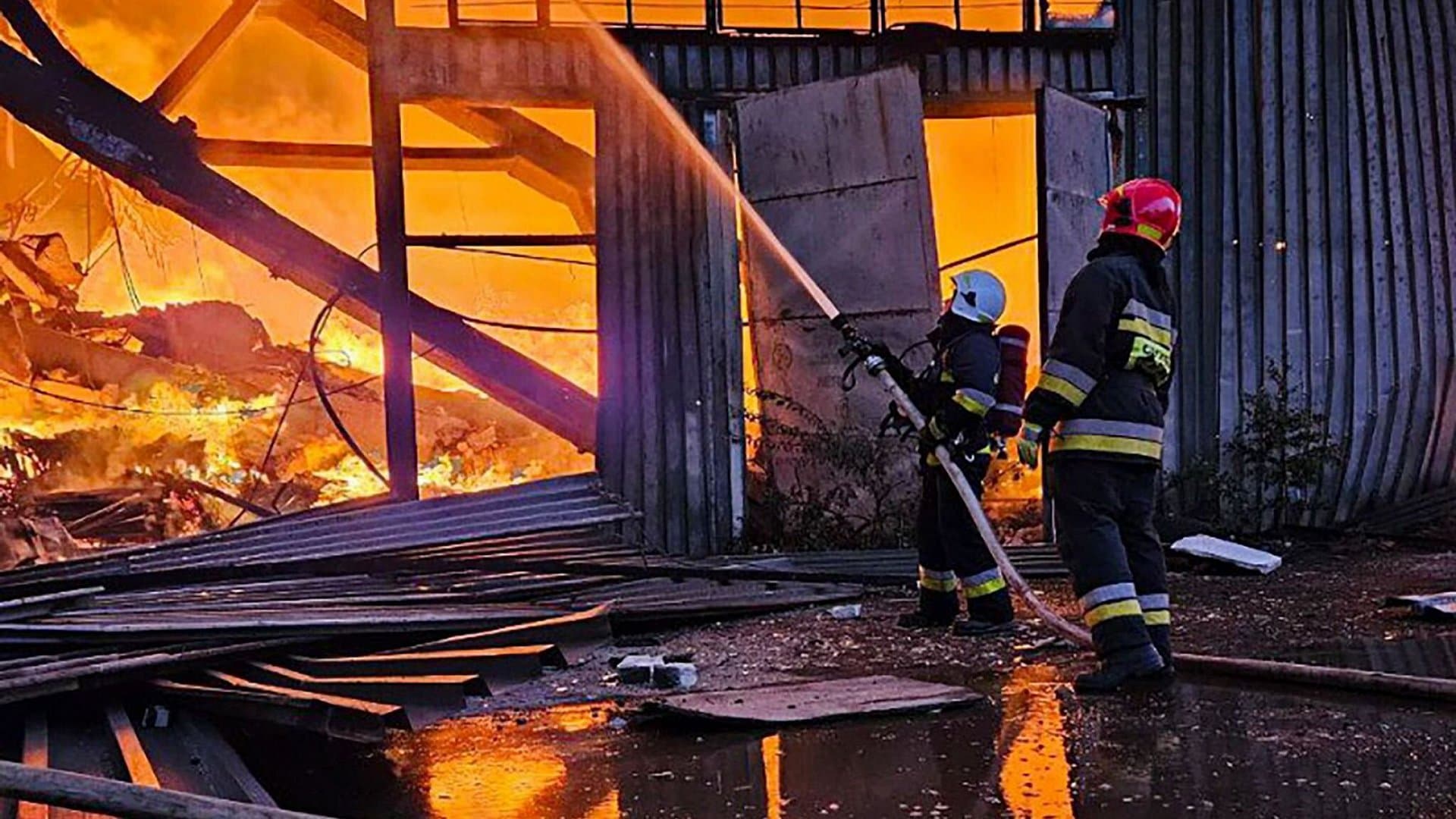 emergency services personnel work to extinguish a fire following a Russian attack in Lviv