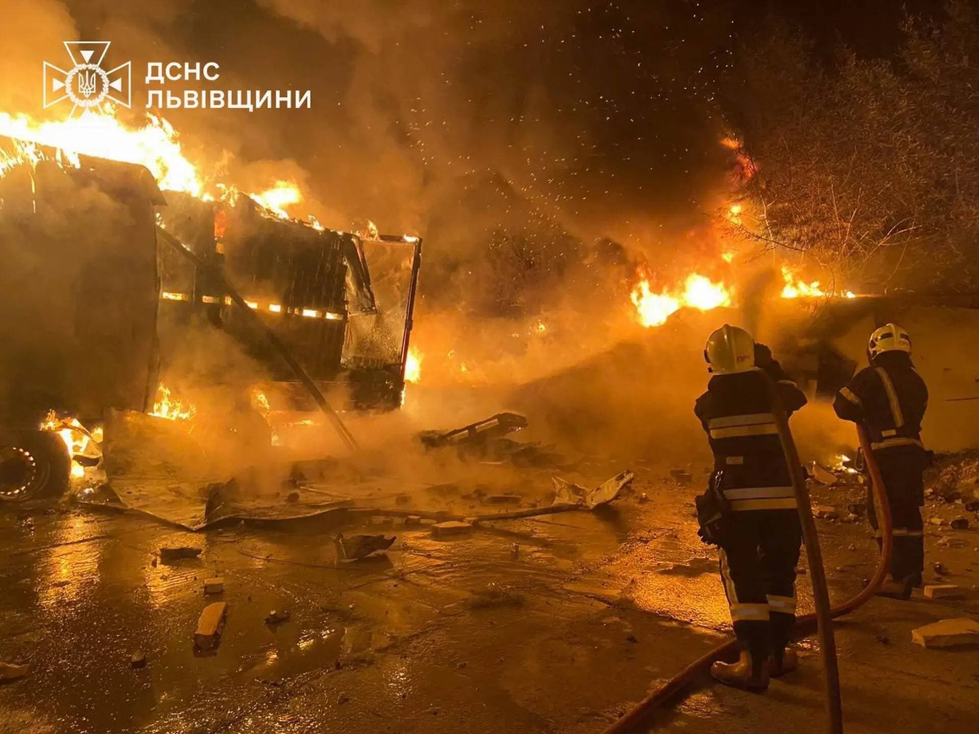 Firefighters extinguish fire in trucks at a site where warehouse facilities were hit during a Russian drone strike in the village of Murovane