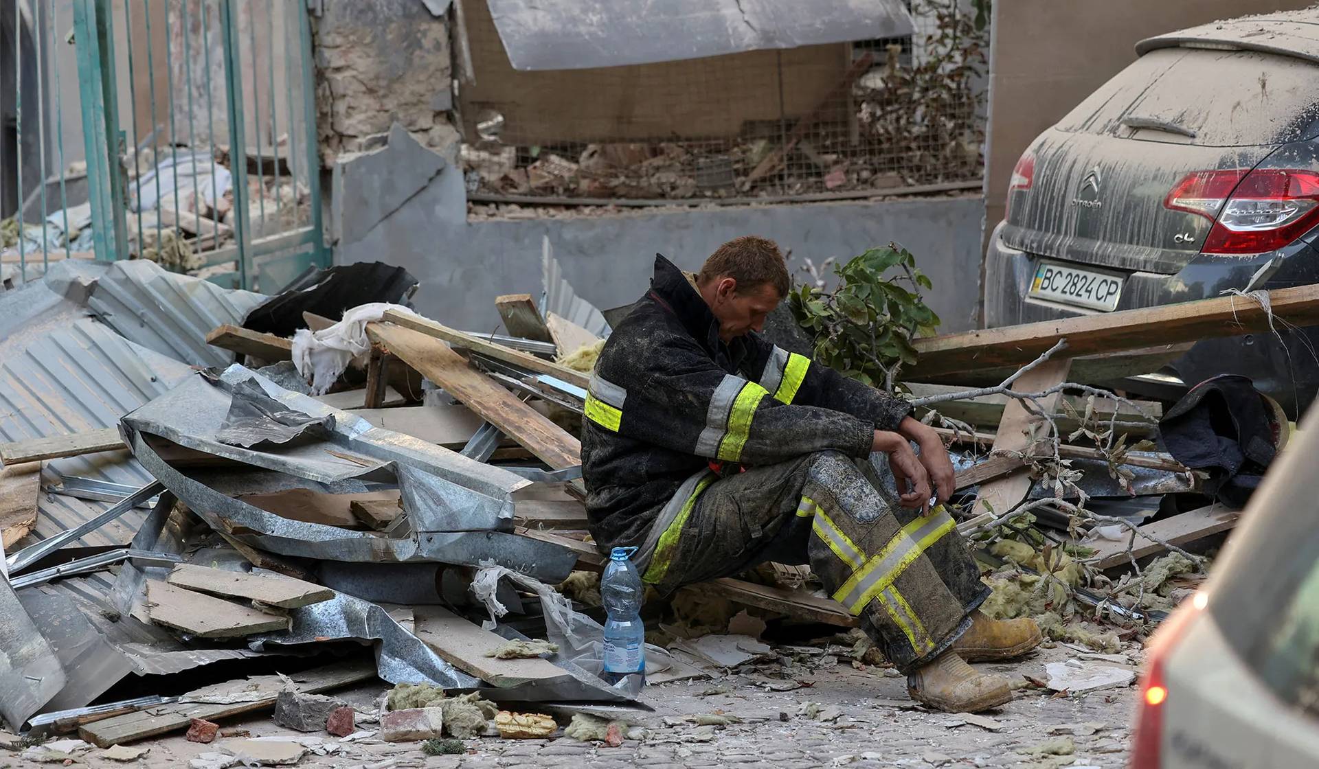 A rescuer rests at the site of a Russian drone and missile strike on residential buildings in Lviv