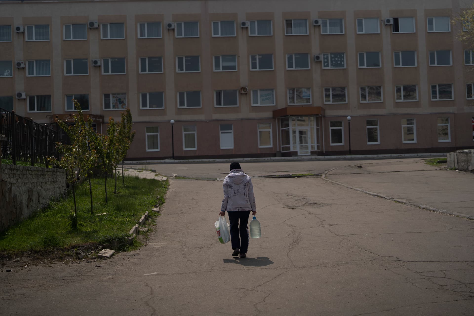 An elderly woman carries a can with water after collecting it from a firefighters truck in Lysychansk