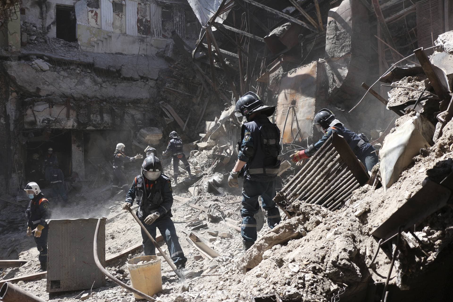 Emergency Situations Ministry employees clear rubble at the side of the damaged Mariupol theater building during heavy fighting in Mariupol