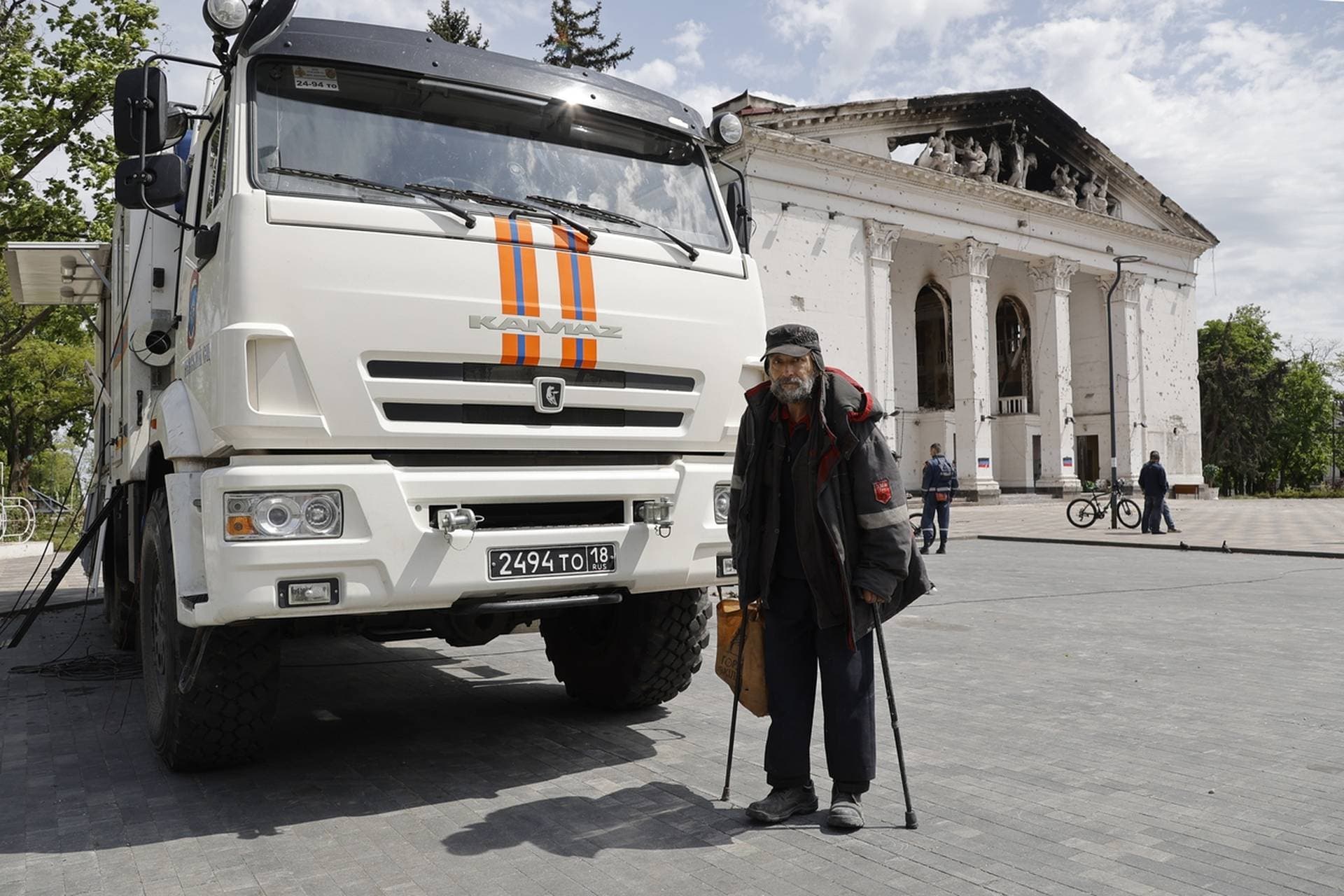 A man walks next to a theater building that has been bombed, in Mariupol