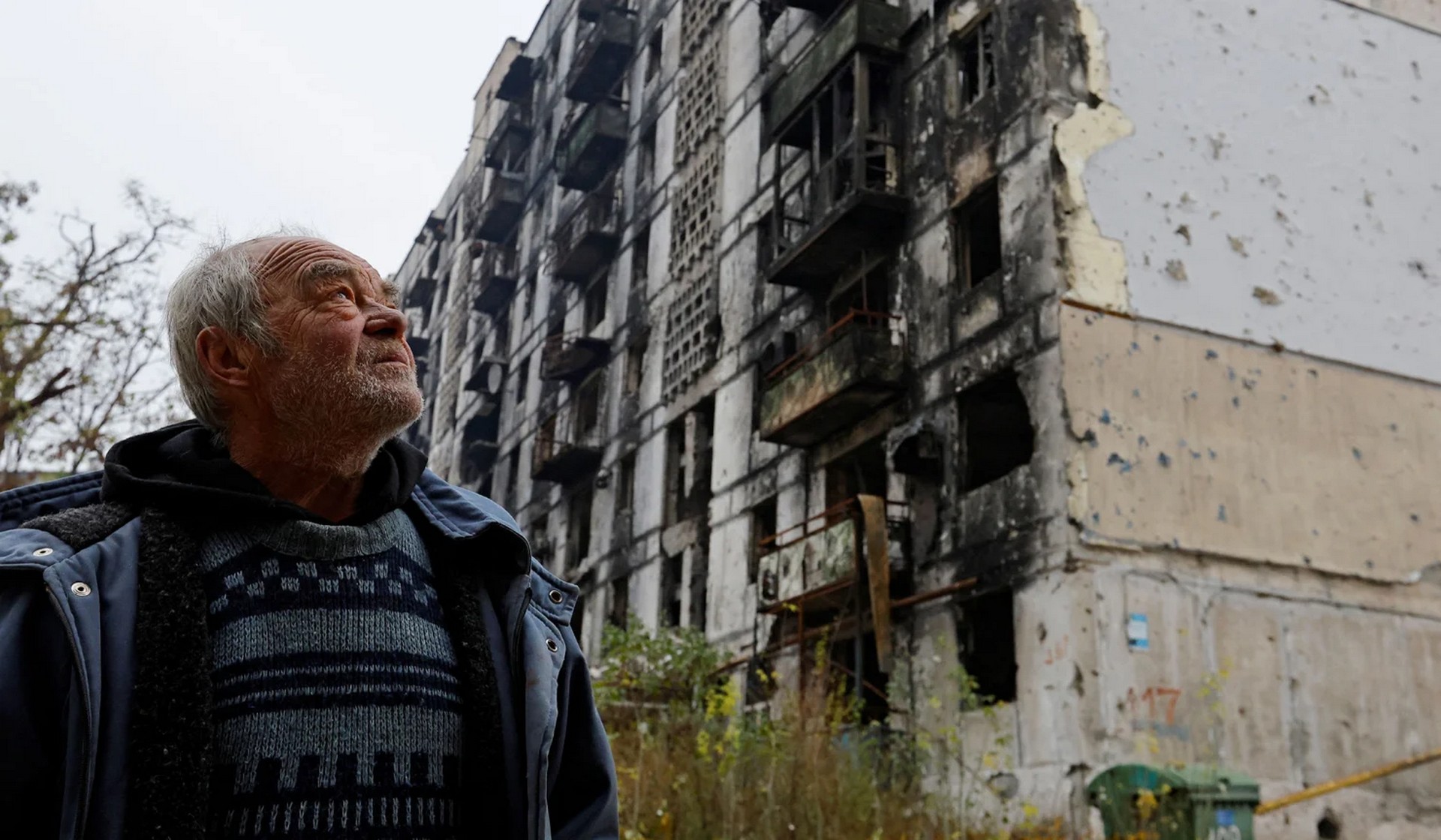 Local resident Pavel Shevtsov stands outside the apartment building where he lives in the basement with his wife Galina after their flat was destroyed in March in Mariupol