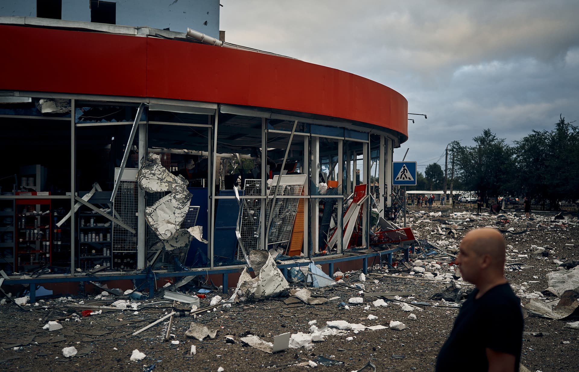 People stand in front of destroyed buildings after the Russian shelling in Mykolaiv
