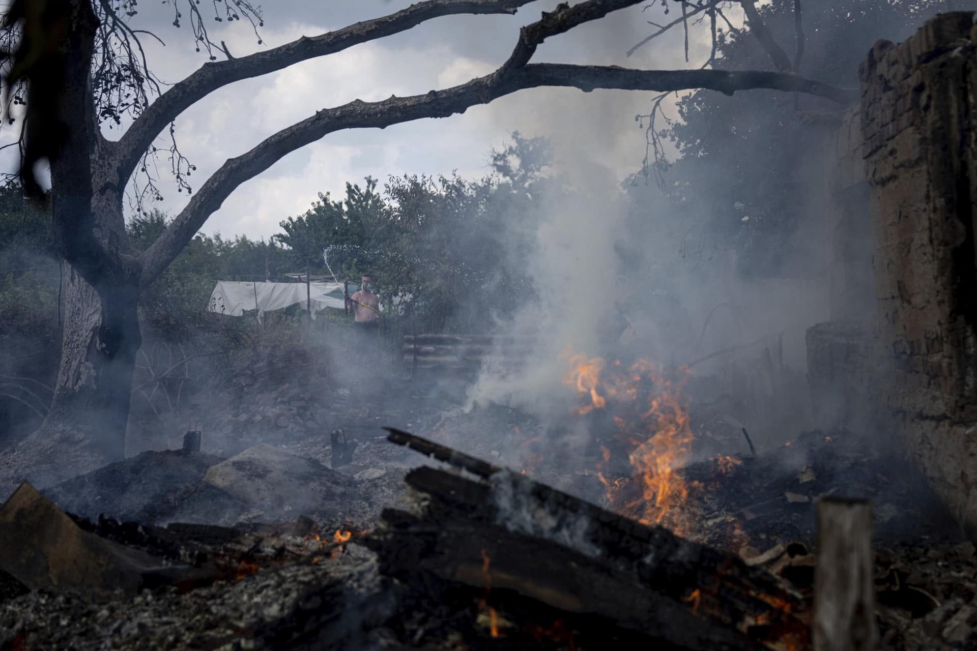 A local resident, back, tries to stop the fire at a neighbor's house destroyed by a Russian attack in Mykolaiv