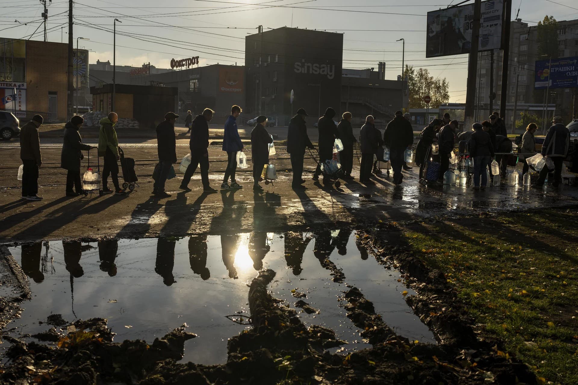 People queuing up hold plastic bottles to refill drinking water from a tank in the center of Mykolaiv
