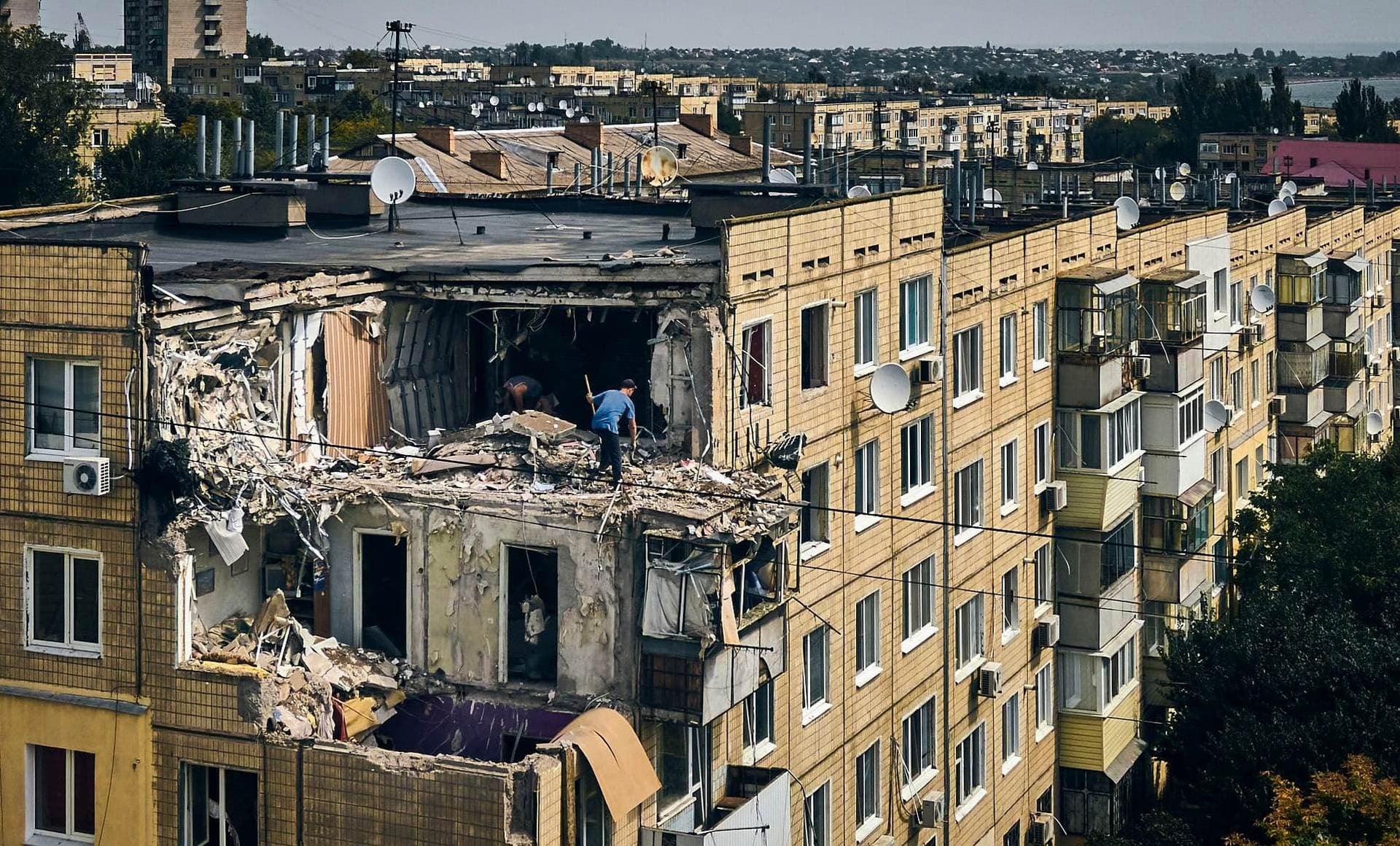 A man cleans an apartment destroyed after Russian shelling in Nikopol