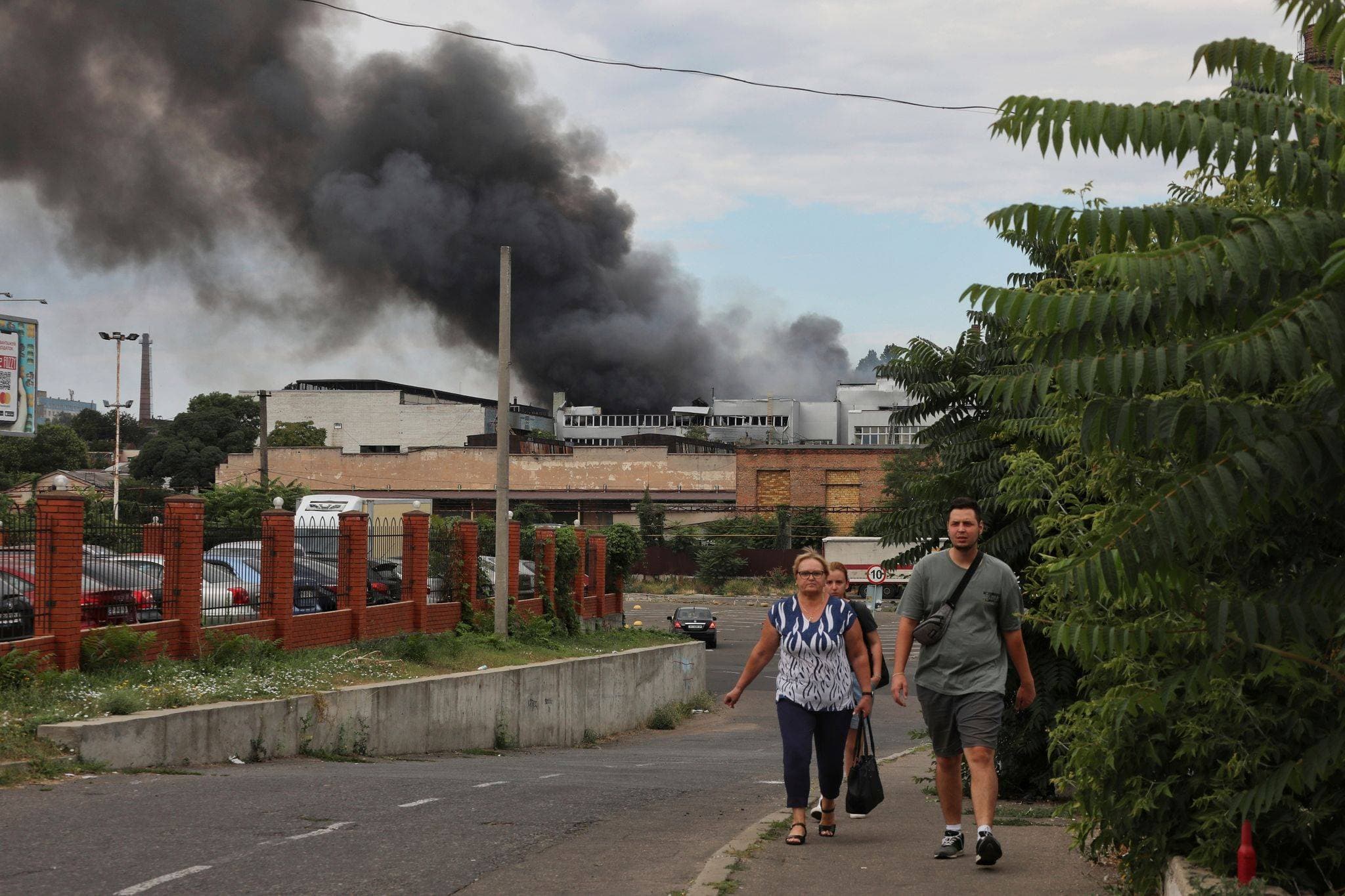 People walk in a street as smoke rises in the air after shelling in Odesa