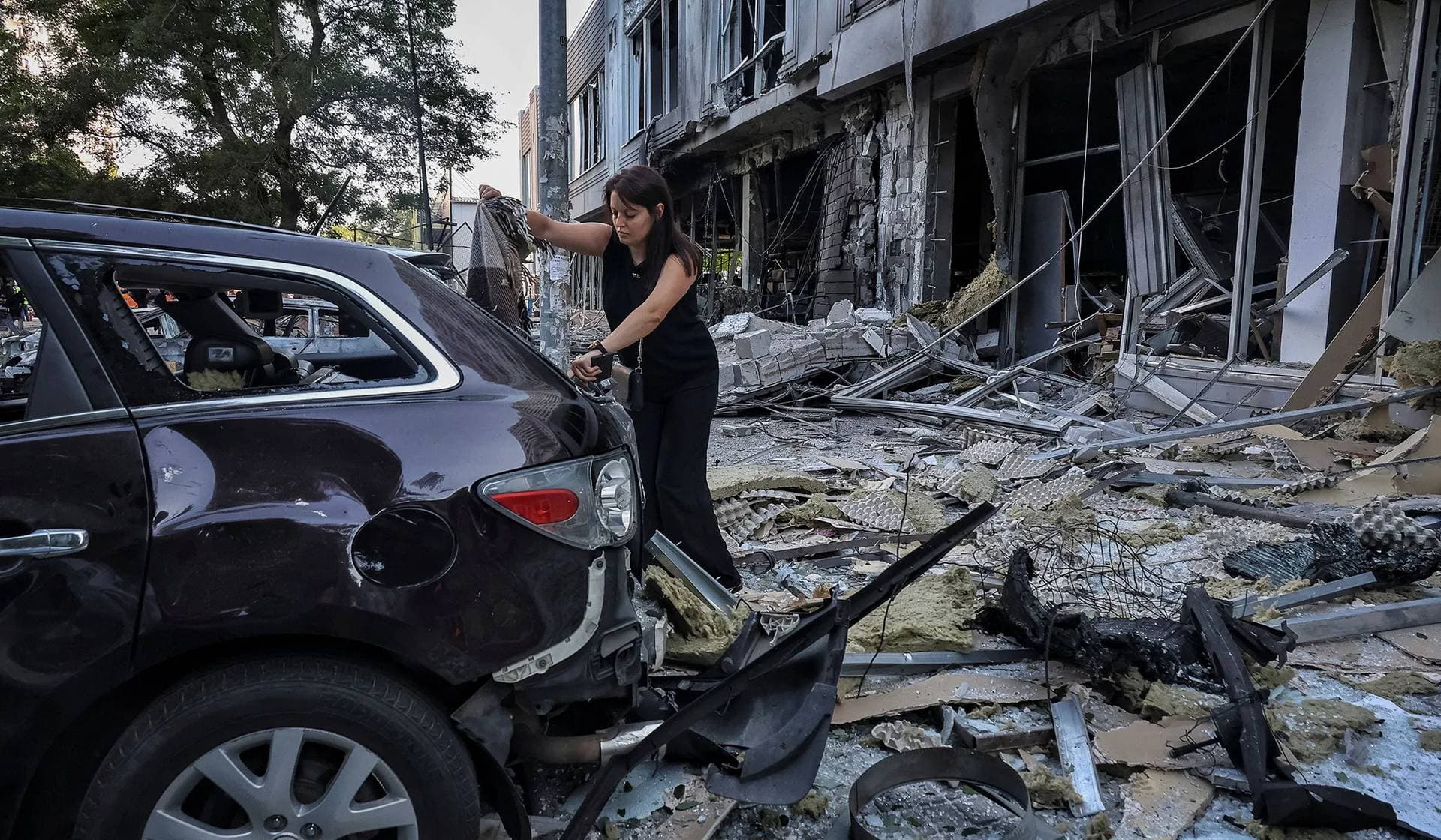 A resident inspects a damaged car at the site of the Russian drone strike in Odesa